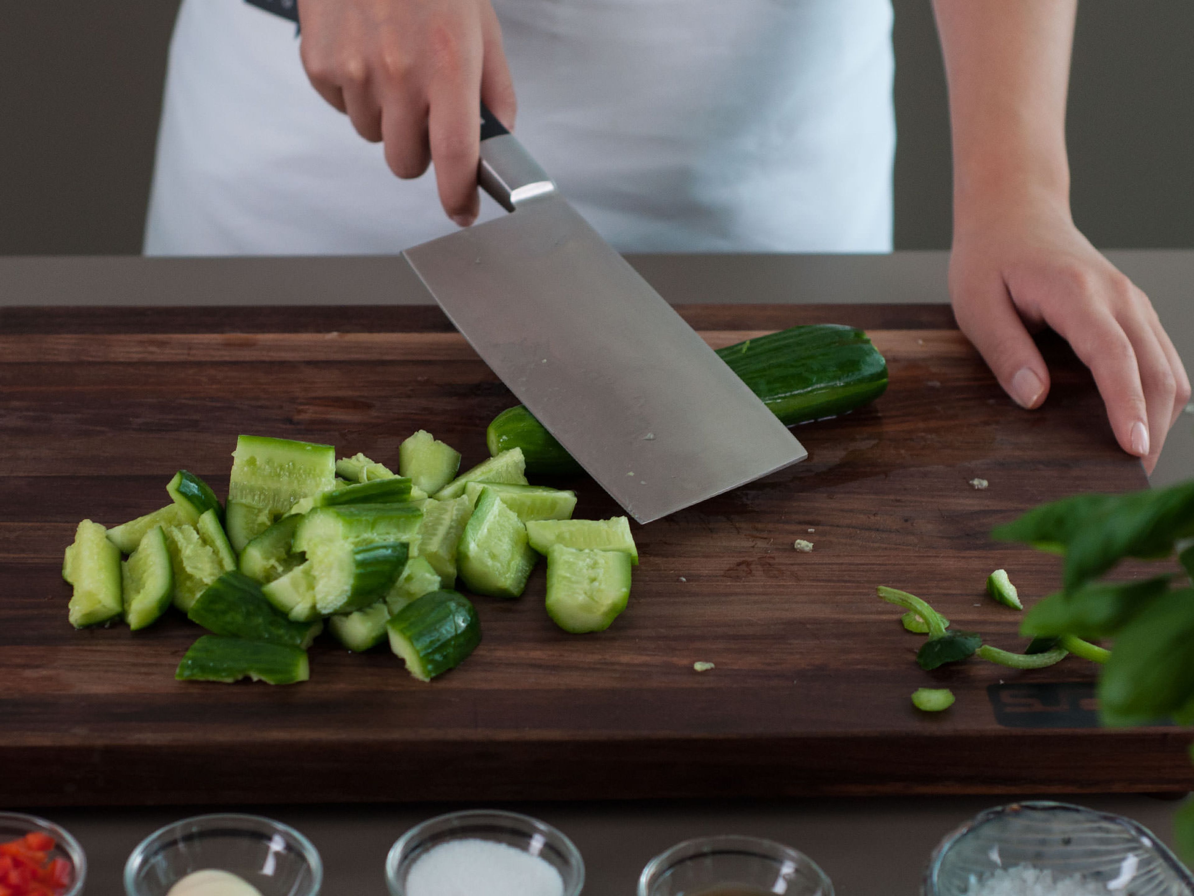 Smash cucumber with a cleaver, cut into thick slices, and transfer to a plate. Crush and mince garlic and sprinkle on top of cucumber. Season with salt and sugar. Drizzle sesame oil on top. Sprinkle diced bell pepper on top. Lightly toss salad and enjoy as a light snack or side dish with Asian fare!