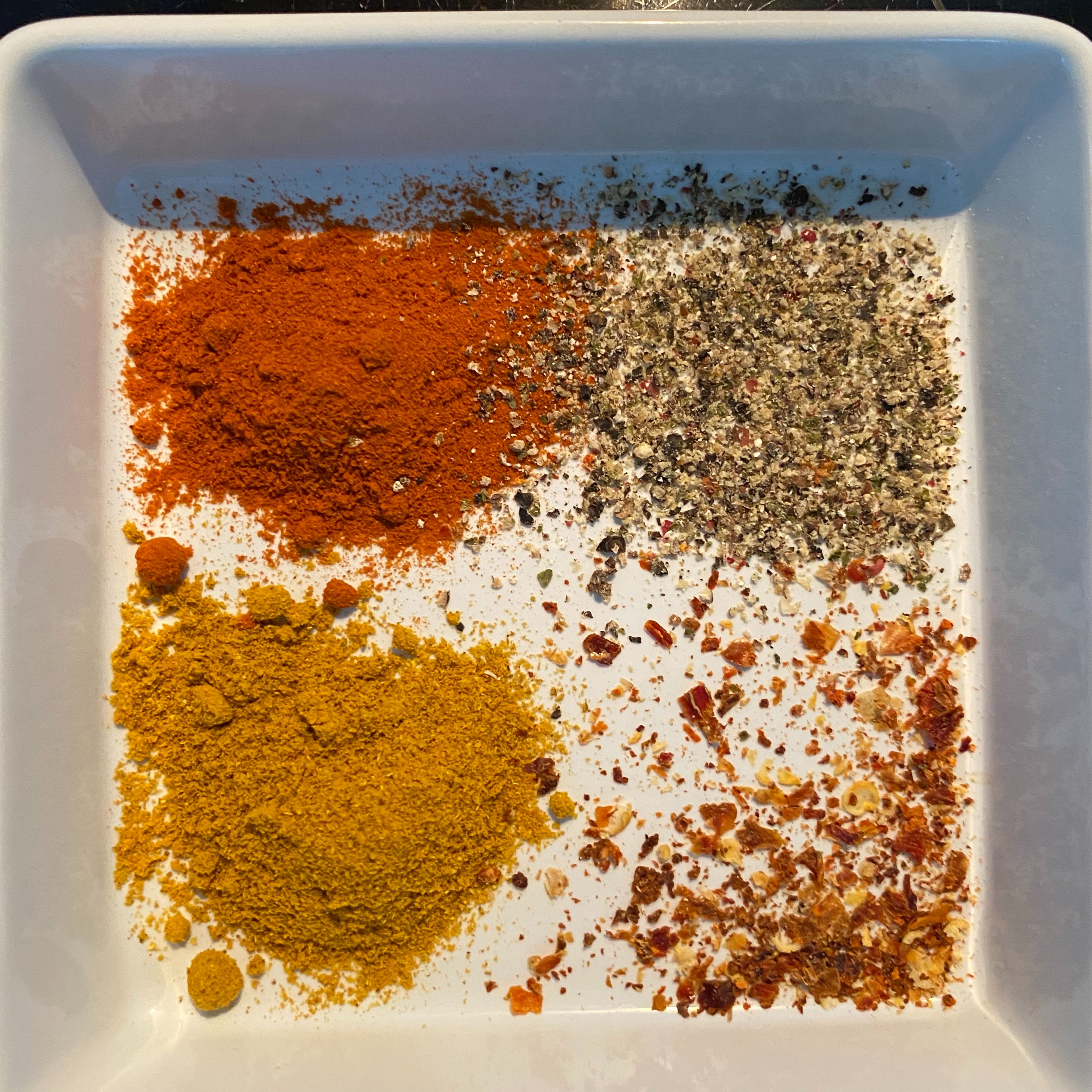 1 EL Currypulver, 1 EL Paprikapulver, 1 TL Pfeffer und 1 TL getrocknete Chili zu den Zwiebeln hinzugeben und im Topf mit einem guten EL Tomatenmark vermengen.