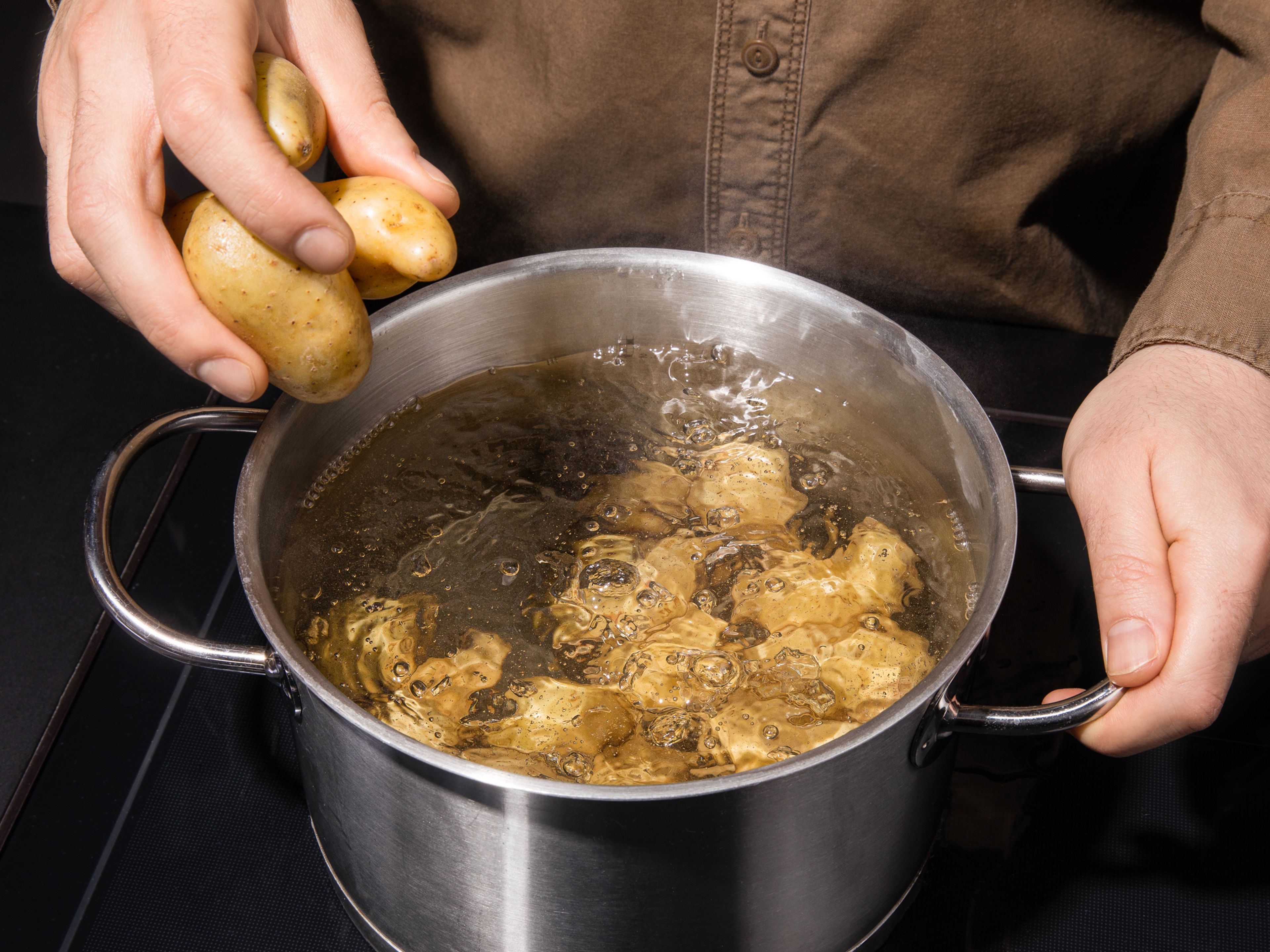 Ca. 3l Wasser in einem Topf zusammen mit dem Backpulver und dem Salz zum Kochen bringen. Sobald das Wasser kocht, die Kartoffeln dazugeben und je nach Größe 10-20 Min. weich kochen. Die Pinienkerne in einer kleinen Pfanne anrösten.