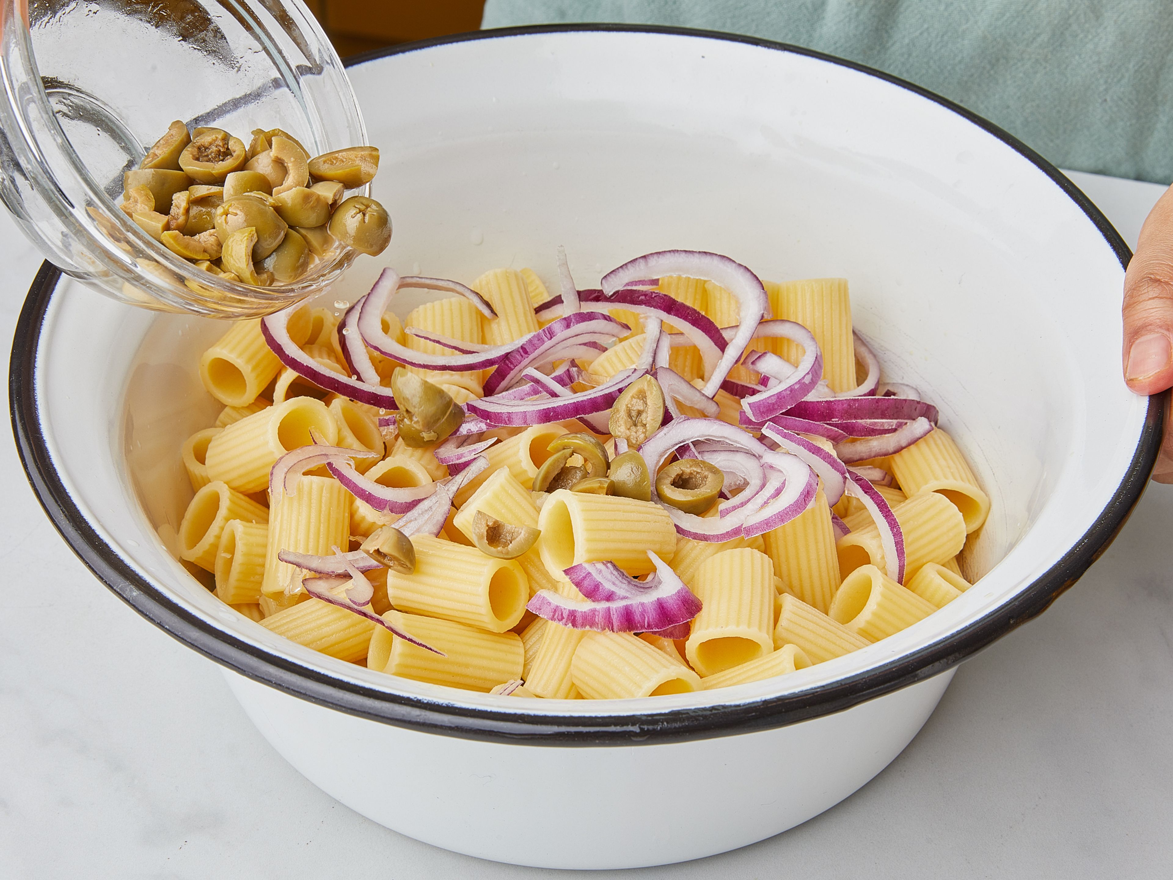 Now add lemon zest and juice, the rest of the drained and raw red onion, olives, herbs and nuts to the pasta and zucchini. Toss together, season with salt and pepper to taste. Serve with some freshly grated parmesan cheese and more oil if desired.