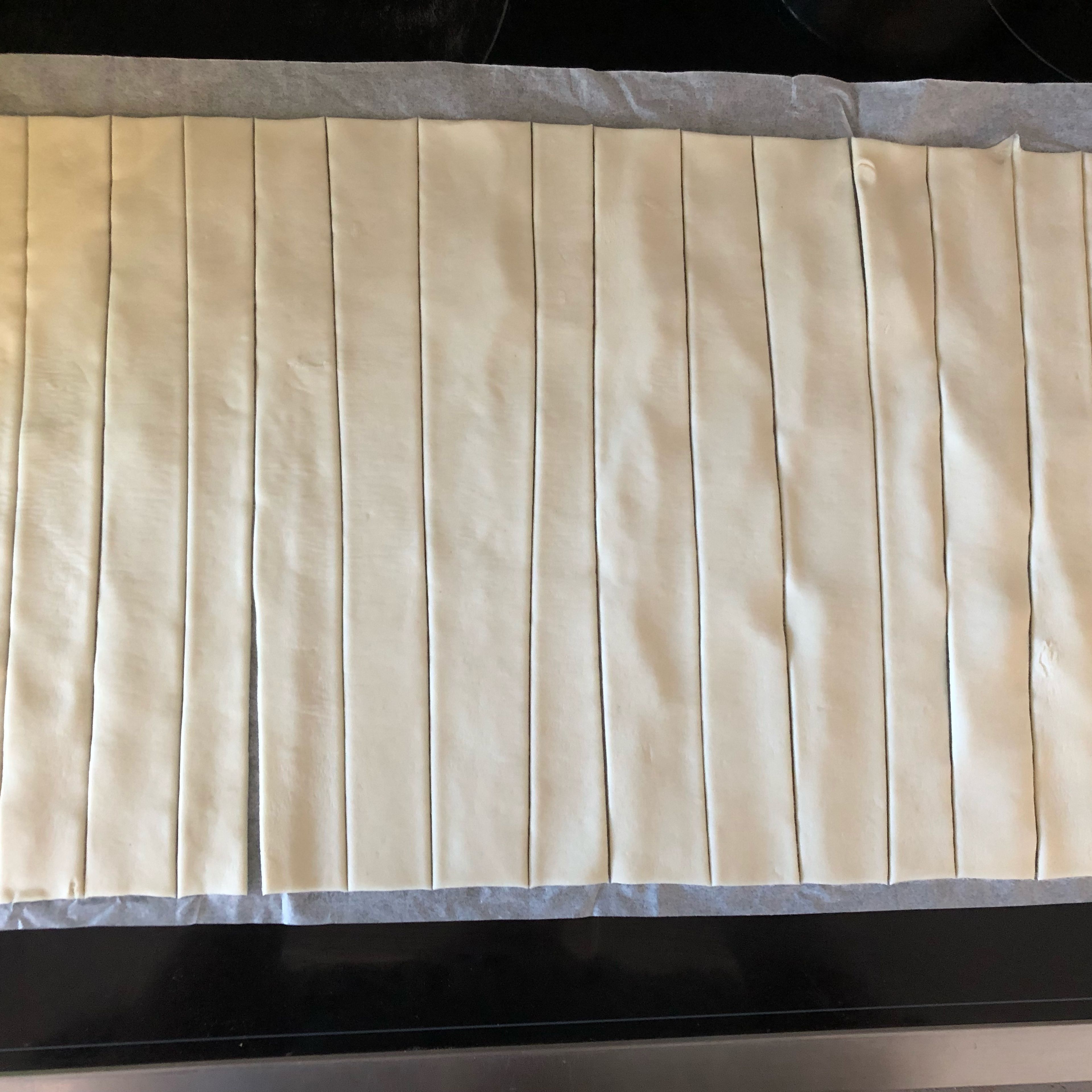 Ofen auf 180 Grad OHUH vorheizen. Blätterteig in 16 gleich breite Streifen schneiden (ca. 1,5 cm). Am leichtesten geht dies mit einem Pizzaschneider.