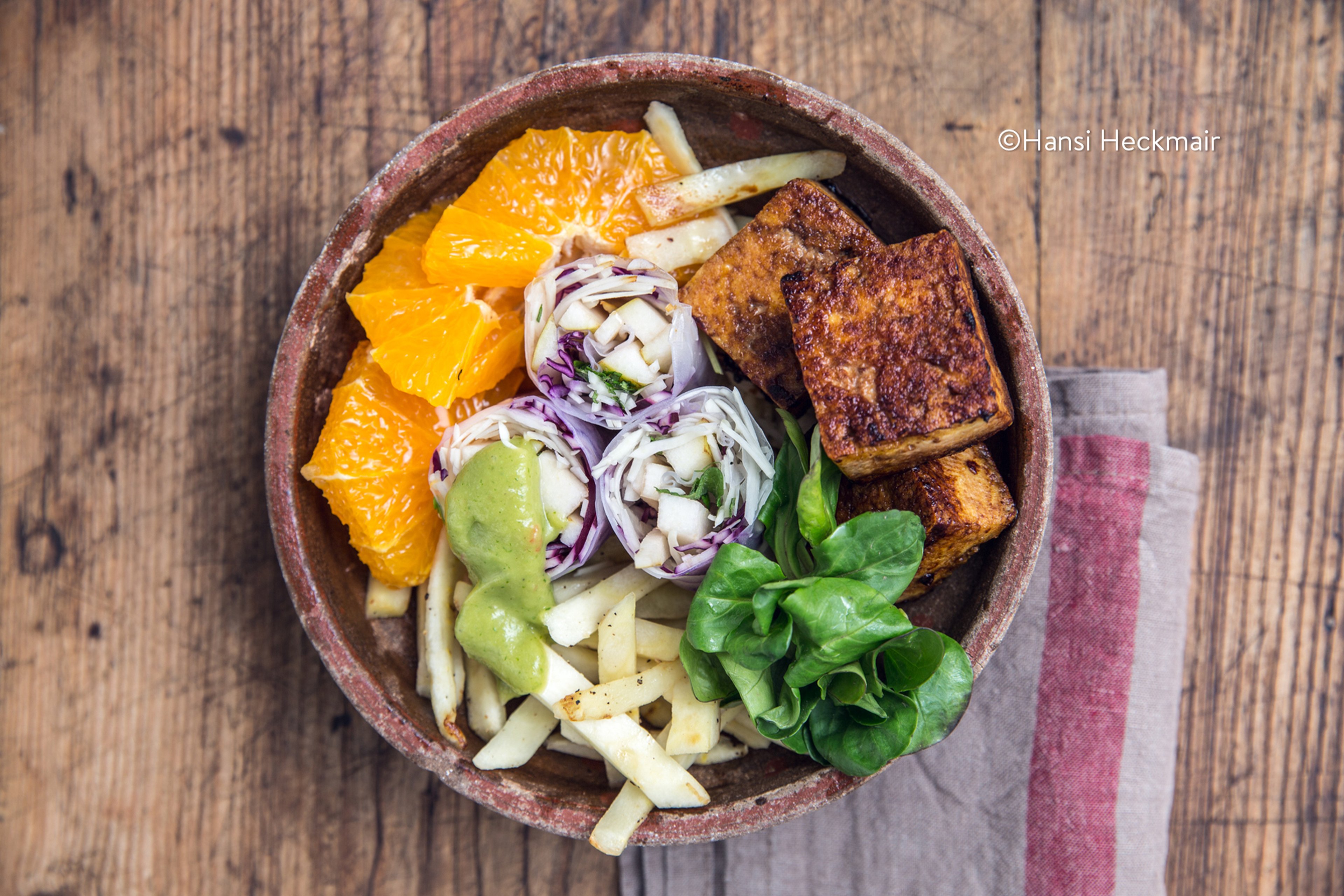 Salad bowl with summer rolls, spicy tofu, parsnips, and orange