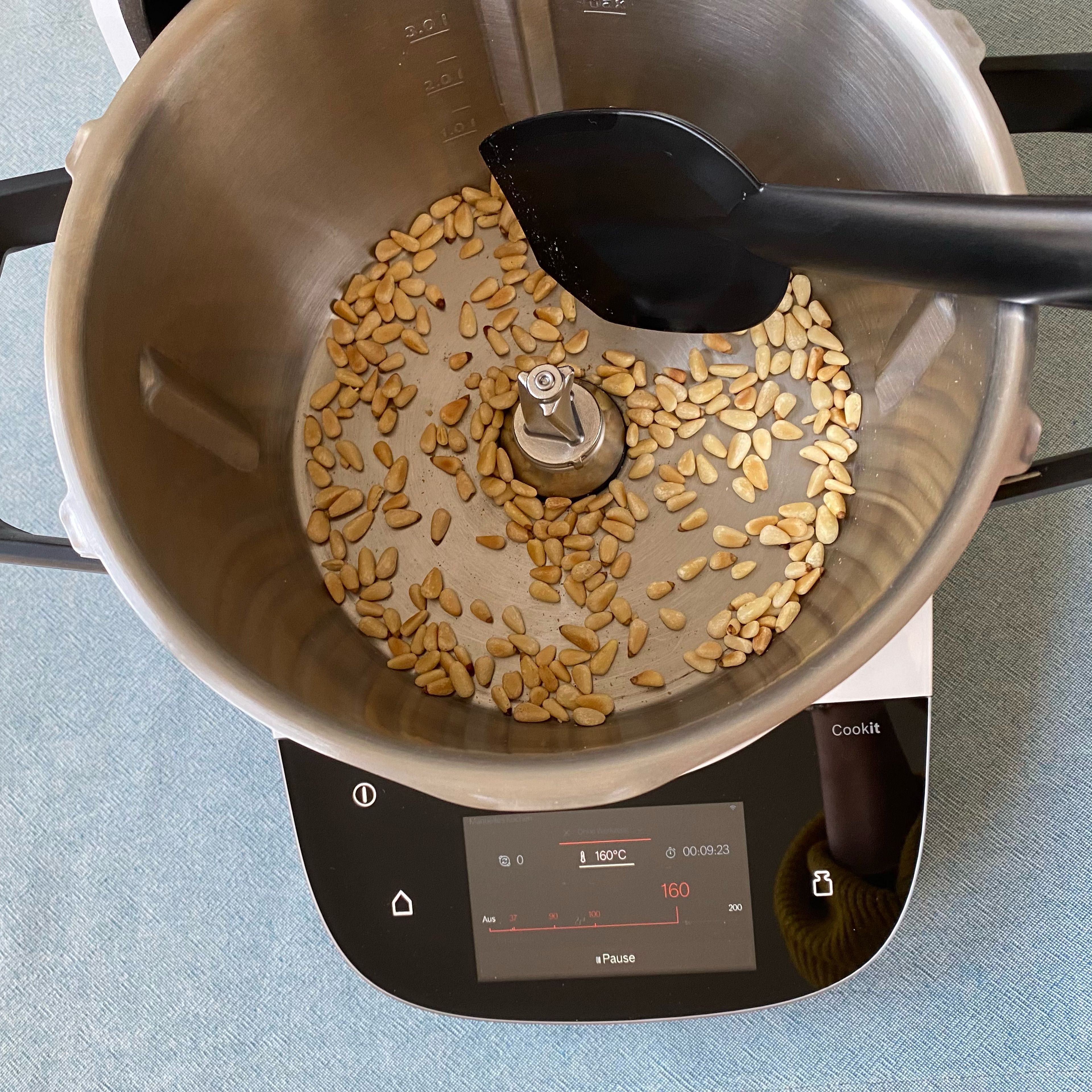 Die Pinienkerne in den Cookit geben und ohne Deckel rösten (ohne Werkzeug | 160°C | 10 Minuten), dabei zwischendurch mit dem Cookit Küchenspatel umrühren. Die goldbraunen Pinienkerne umfüllen.