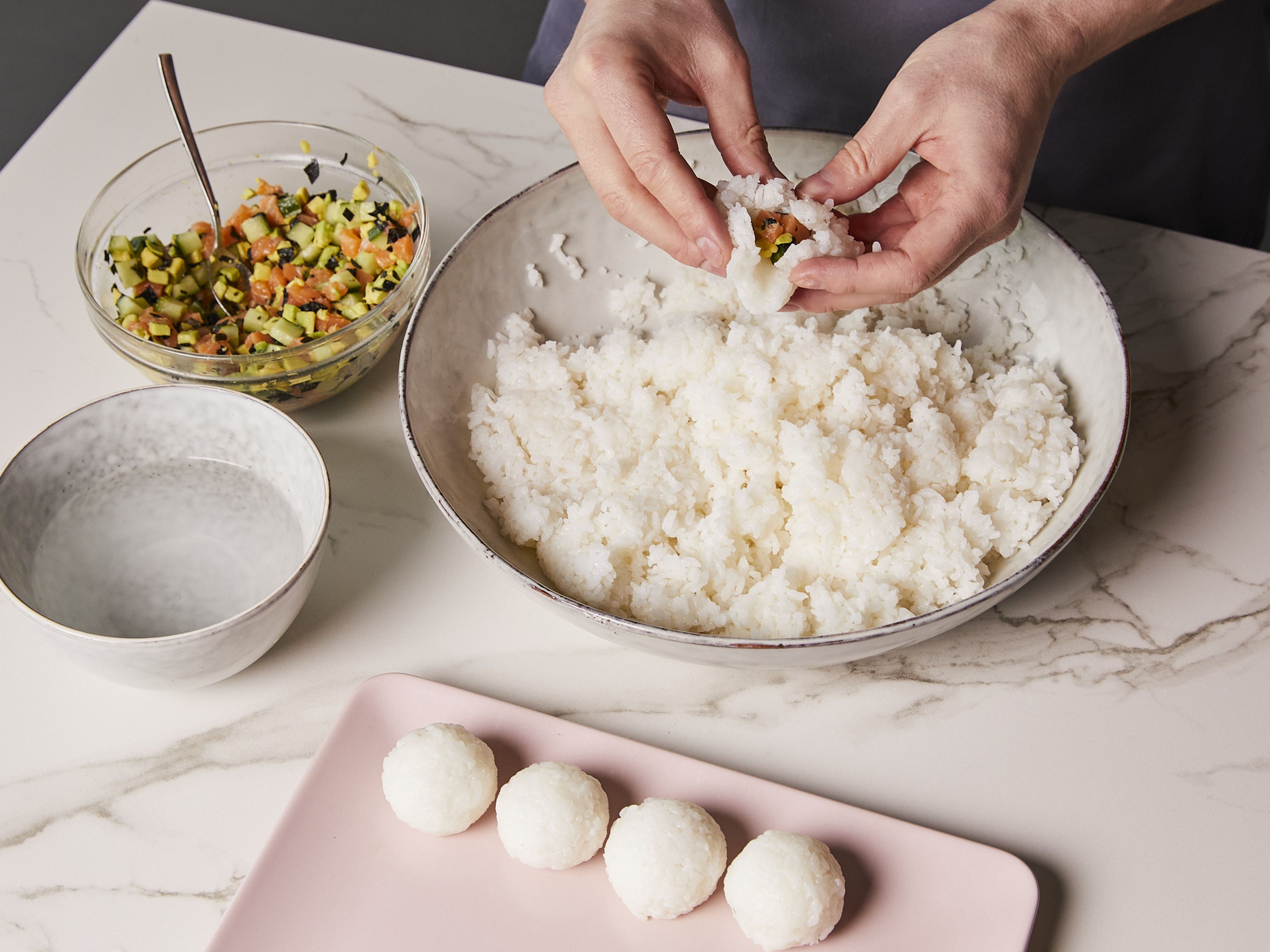 With wet hands, take a small handful, approx. the size of an egg, of the cooled rice and form into a ball, then press into the center with your thumb to create a small crater. Pour in a little of the filling, approx. 1 tsp, close the ball tightly and repeat until the rice is used up.
