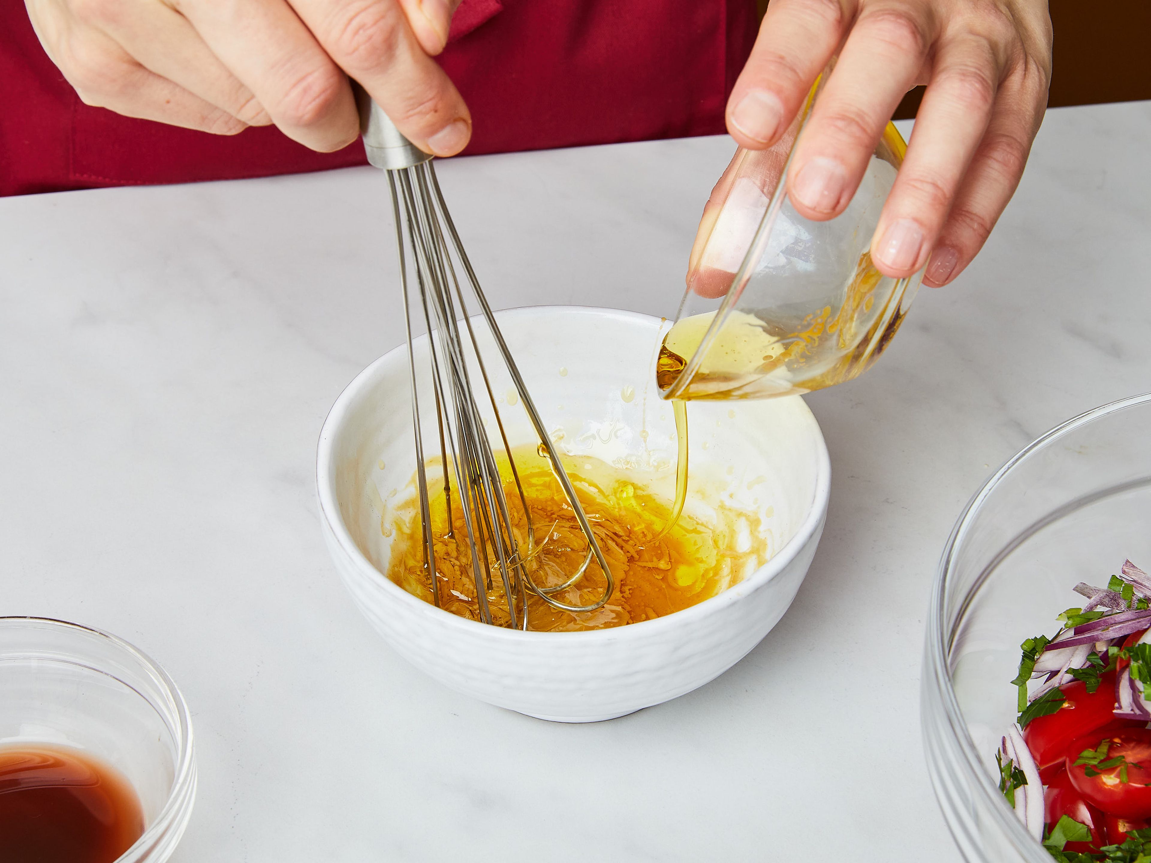 Den Salat in Blätter zerteilen und auf eine große Servierplatte legen. Kirschtomaten halbieren und in eine große Schüssel geben. Petersilie grob hacken und in die Schüssel geben. Die rote Zwiebel in feine Scheiben schneiden und ebenfalls in die Schüssel geben. Für das Dressing, Senf und Honig in eine kleine Schüssel geben. Langsam die Hälfte des Olivenöls einrühren, um es zu emulgieren, dann den Essig einrühren. Grob gemahlenen Pfeffer hinzufügen und mit Salz abschmecken. Beiseite stellen.