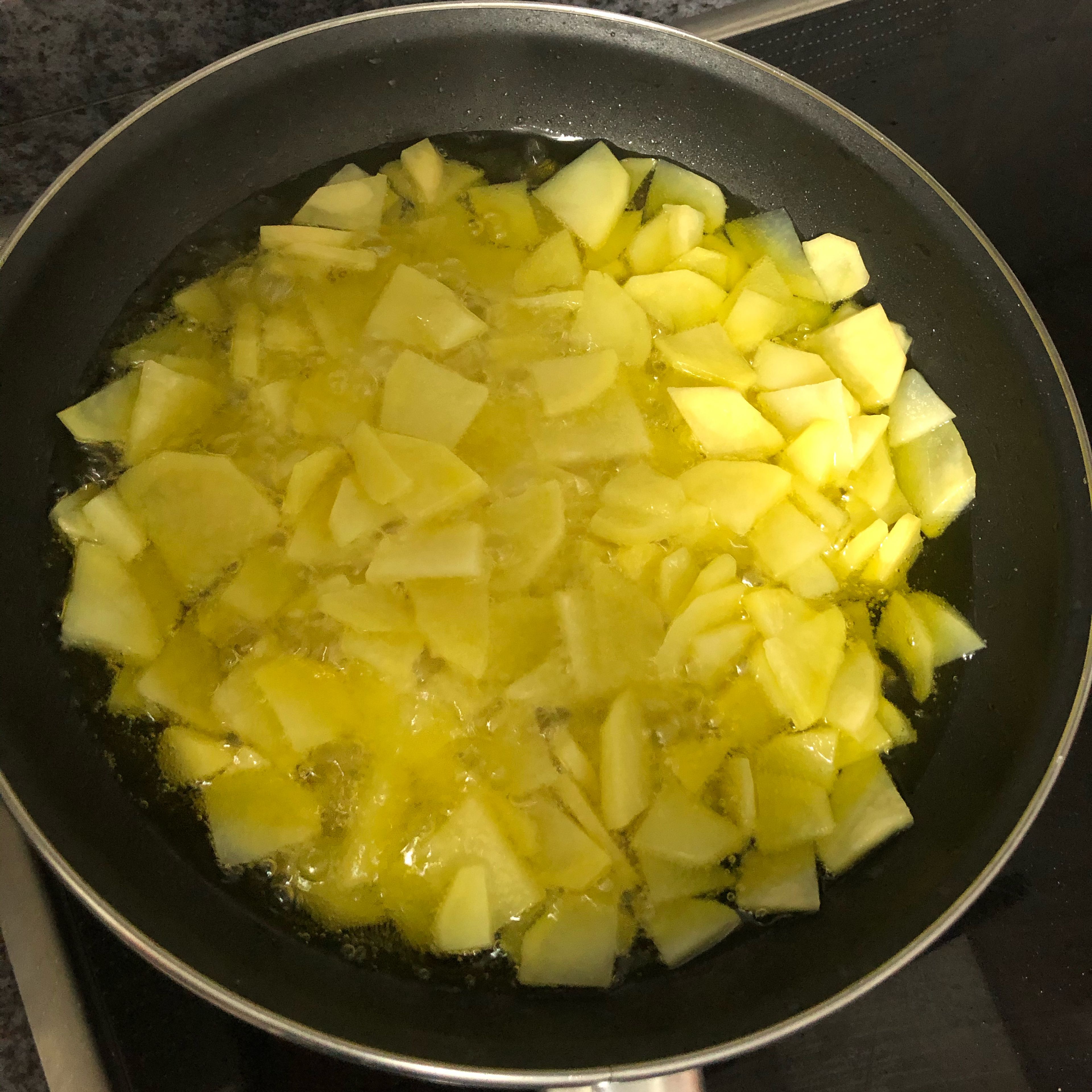 In abundant oil, let the potatoes cook on medium heat for about 20 minutes. Add a bit of salt. You want the oil to cover the potatoes. Every 5 minutes, stir the potatoes to make sure that all the slices are cooked.