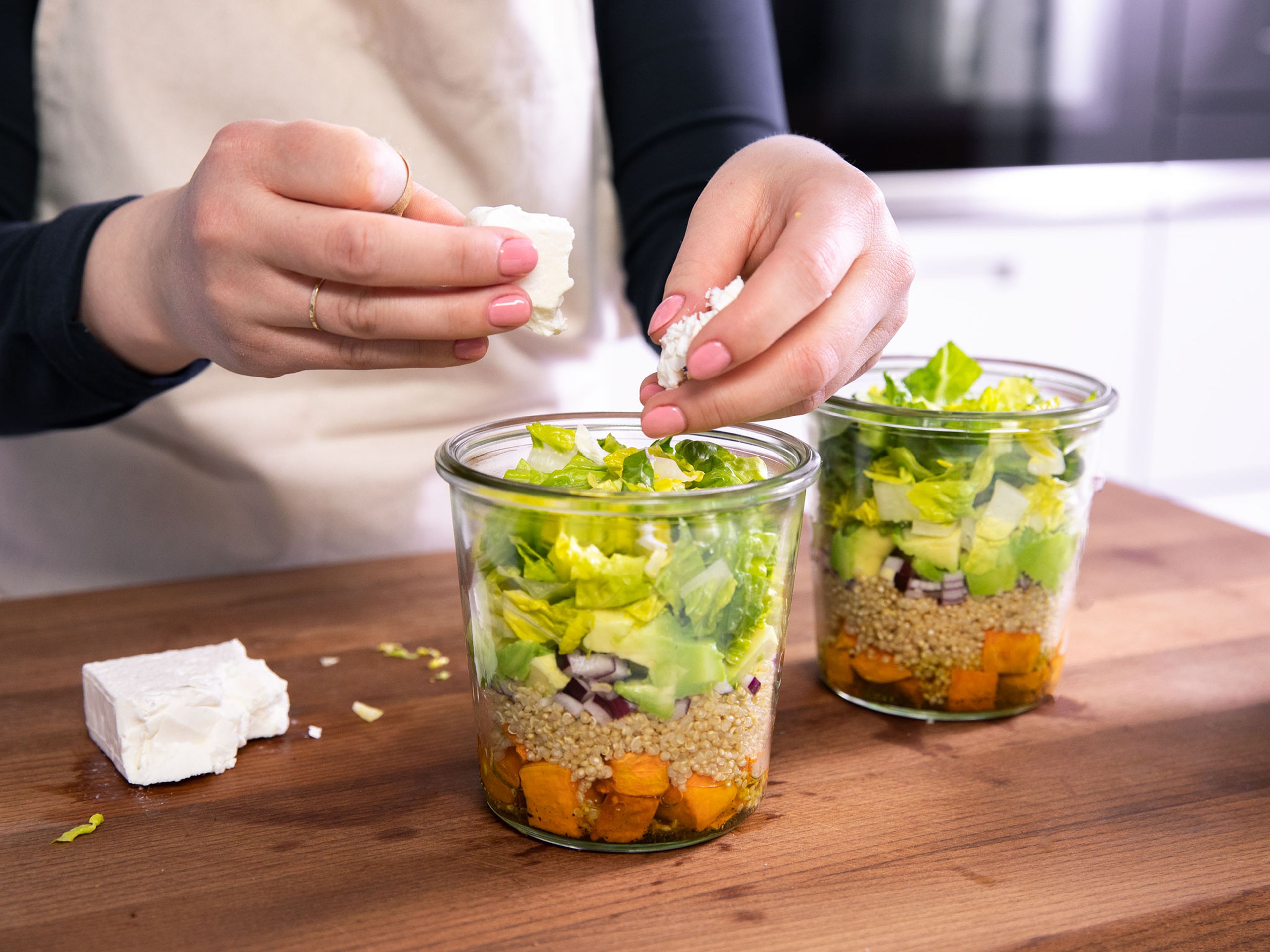 Start layering the salad with the dressing first and divide it equally to jars. Top with sweet potato, quinoa, red onion, avocado, and romaine lettuce. Crumble feta cheese with your hands and add on top, then finish with toasted sunflower seeds. Enjoy right away or store in the fridge for 1-2 days.