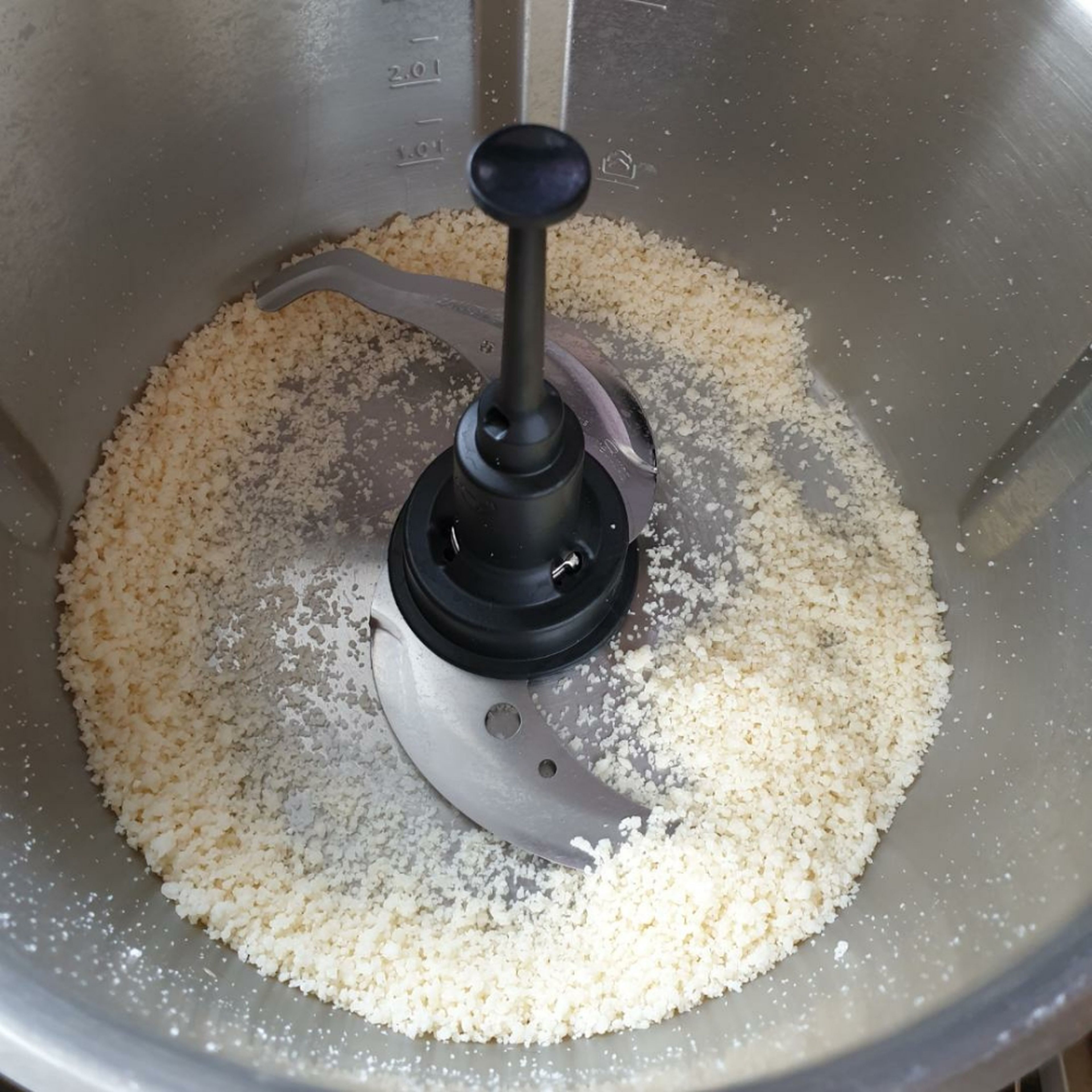 Das Universalmesser in den Cookit einsetzen. Den Parmesan in ungefähr 2 cm große Stücke schneiden und in den Topf geben. Den Deckel schließen, den Messbecher einsetzen und den Parmesan zerkleinern (Universalmesser | Stufe 13 | 45 Sekunden). 
Den zerkleinerten Parmesan aus dem Topf in eine Schüssel geben.