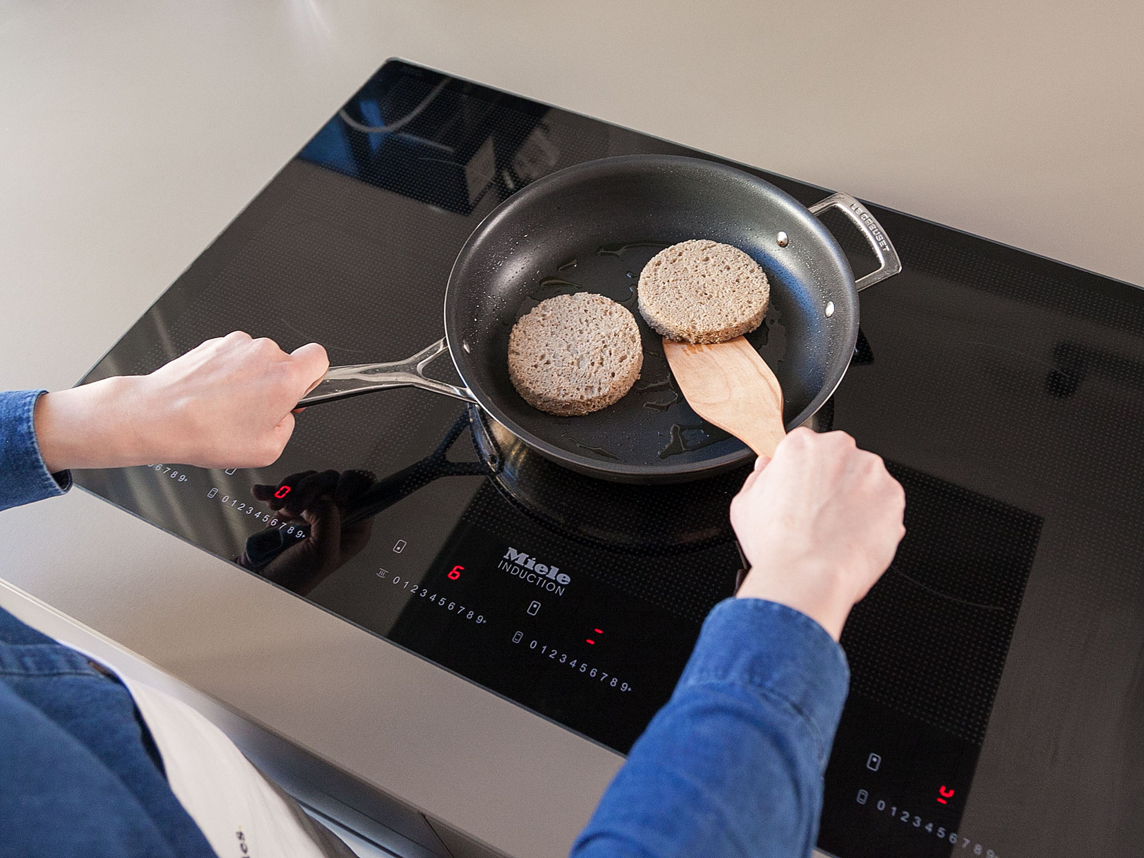 With the help of a cake ring, cut out two circles approx. the size of the burger patties from each slice of bread. They will be used as buns later. Heat oil in a frying pan over medium-high heat and toast bread on both sides for approx. 2 min., or until crisp.