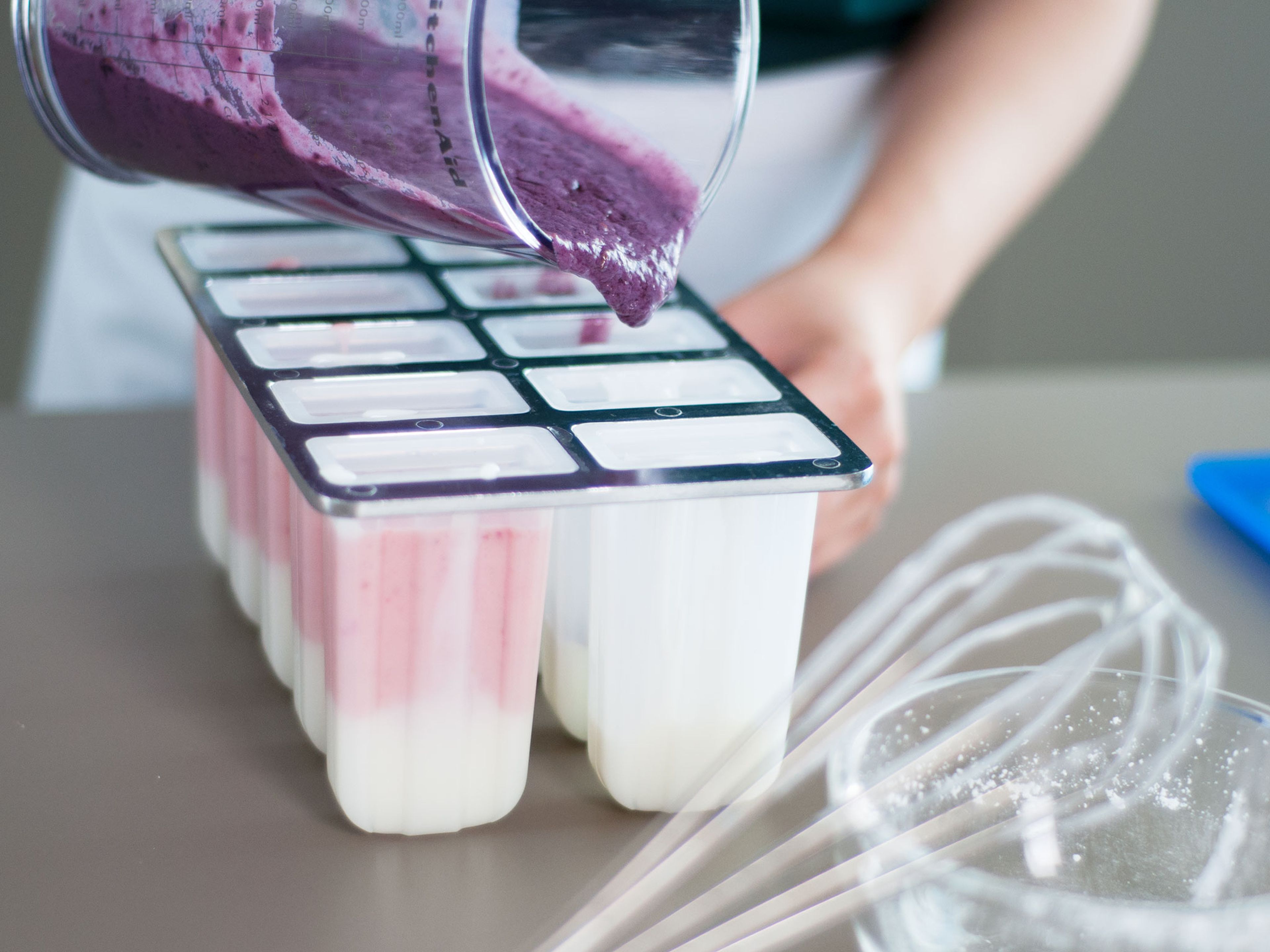 Erdbeer-Joghurt-Mischung auf eine Hälfte der Förmchen verteilen und Brombeer-Joghurt-Mischung auf die andere Hälfte.  Für 4 - 5 h in den Gefrierschrank stellen.