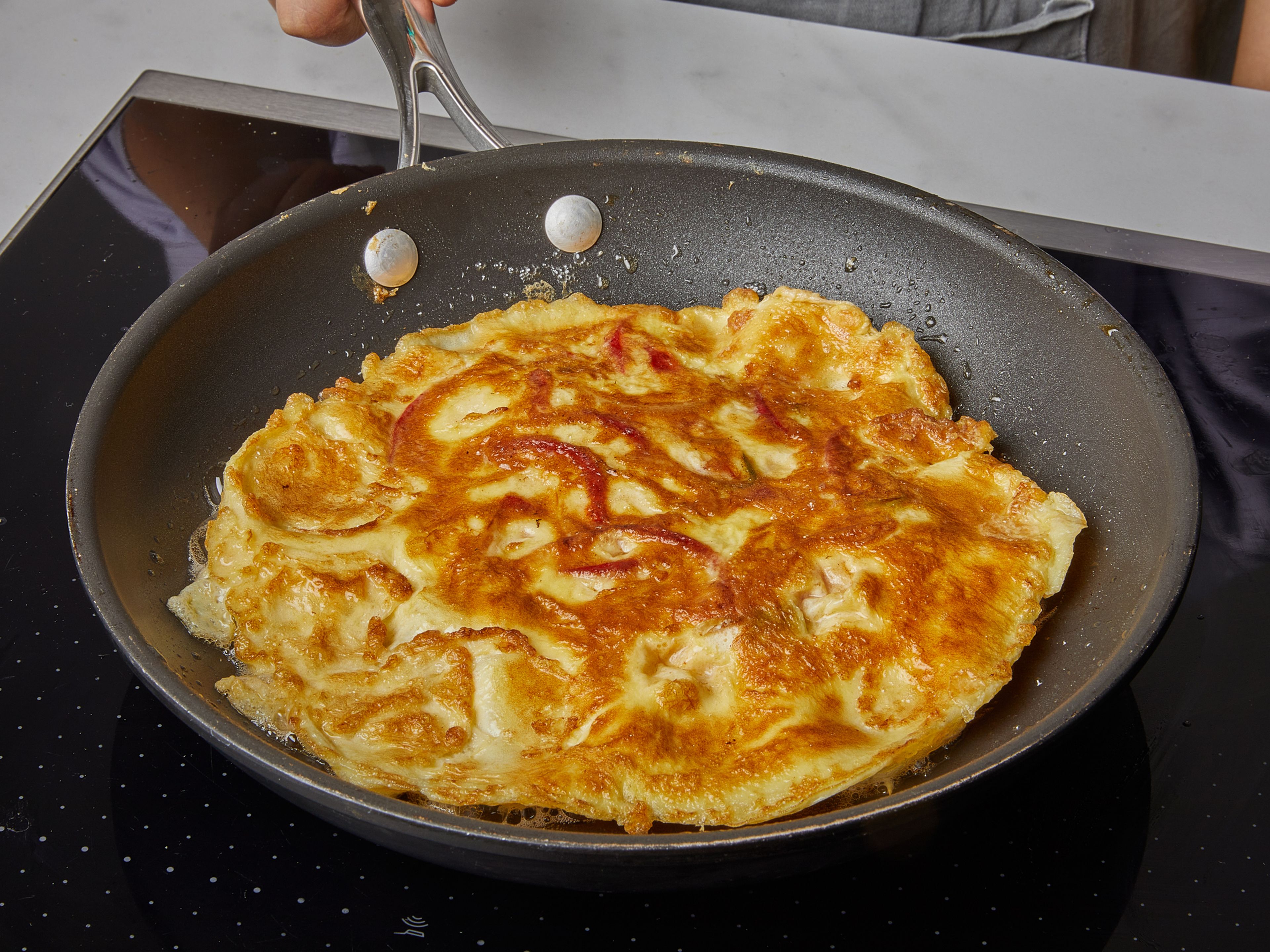 Wipe out the pan and add some vegetable oil. Heat over medium-high heat. When the oil is hot, add half the egg mixture; the edges should puff right when it hits the hot pan. Lower the heat,  and cook until the top of the omelette is set. Then use the help of a spatula to flip, and fry until the other side is golden brown. Remove from the pan and repeat with more and remaining egg mixture.