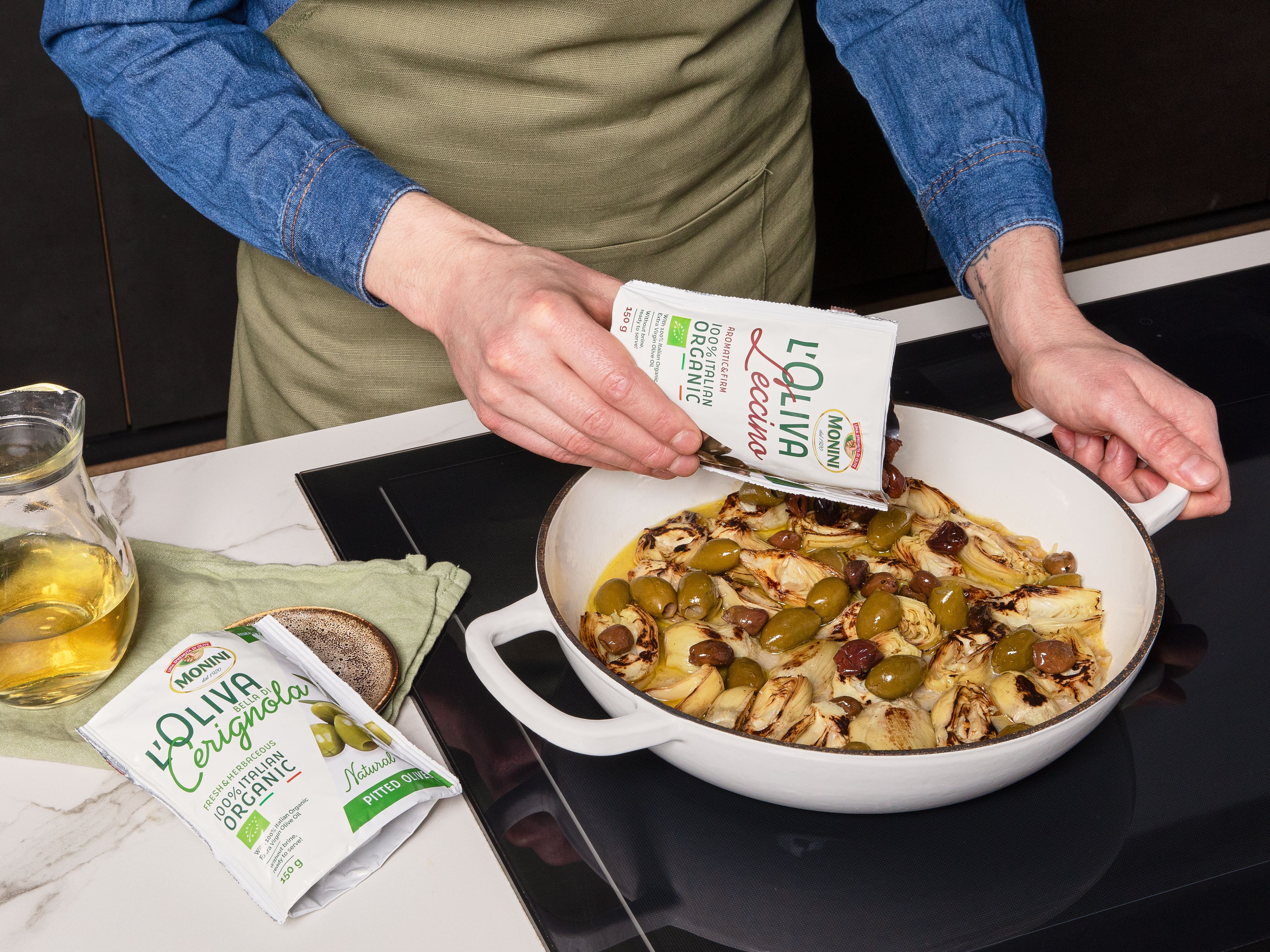 Die Schalotten in die zuvor verwendete Pfanne geben und ca. 2–3 Min. anbraten, bis sie weich sind. Den Knoblauch hinzufügen und ca. 1 Min. mitbraten, bis er duftet, dann alles mit Weißwein und Hühnerbrühe ablöschen. Die Artischocken sowie die Monini Leccino und Sant'Agostino Oliven dazugeben. Dann die Mischung zum Köcheln bringen und ca. 3–4 Min. köcheln lassen, bis alles erhitzt ist und die Soße leicht reduziert ist.