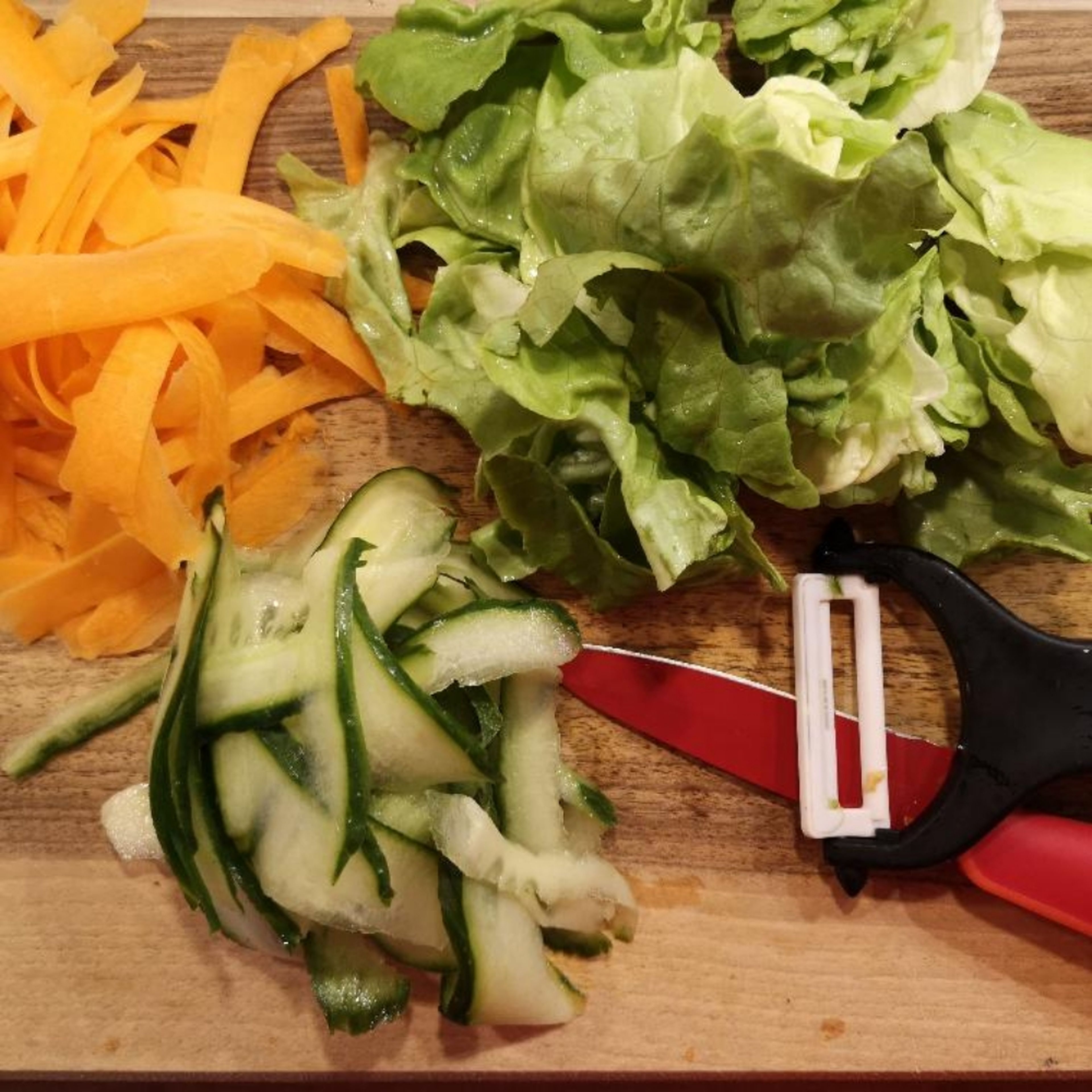 Die Karotte schälen und mit dem Gemüsehobel in mittelgroße Streifen hobeln. Die Gurke ebenso hobeln. Einige Salatblätter waschen und auf die gewünschte Essgröße bringen.