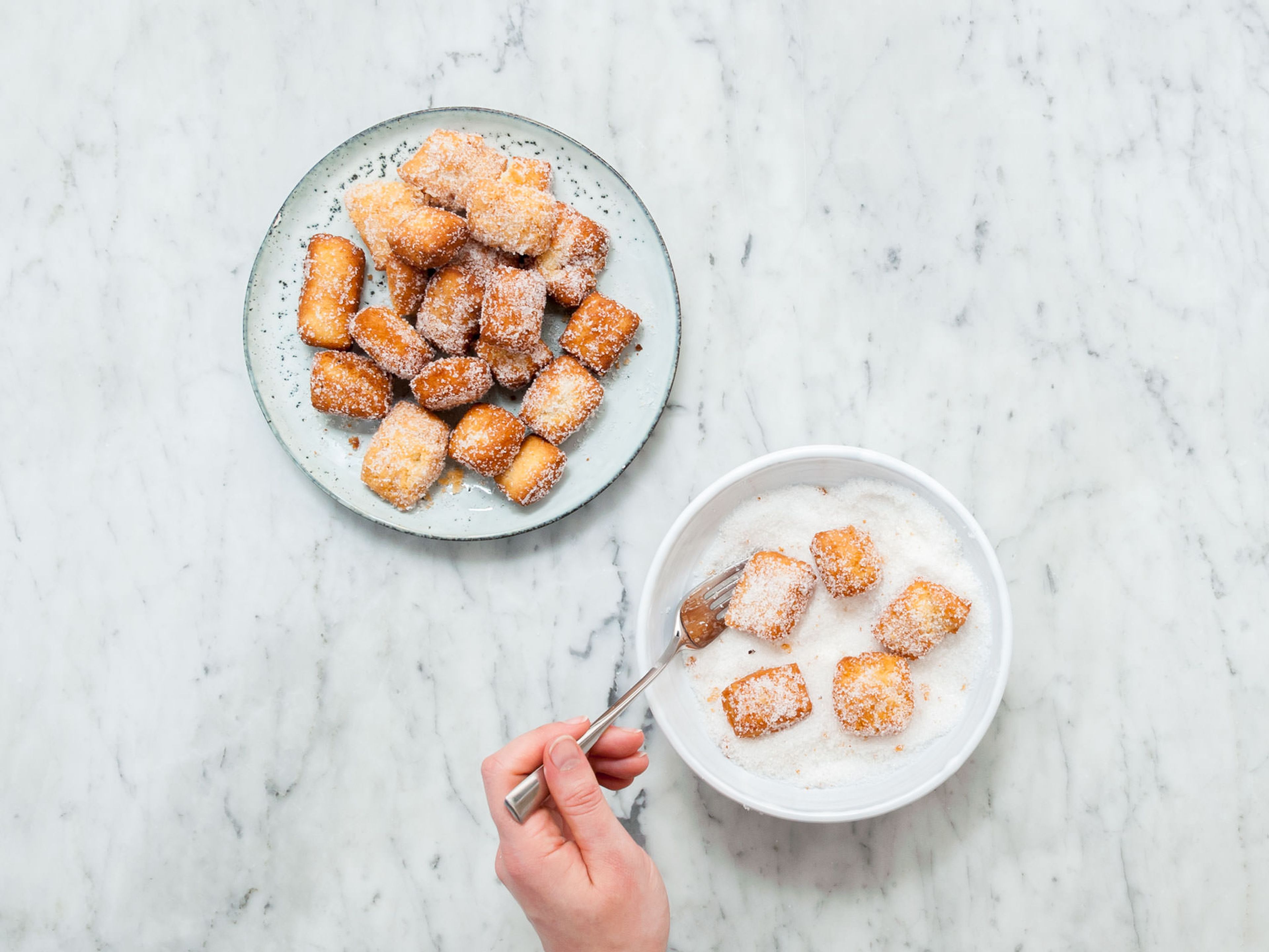 Transfer sugar onto a plate and roll deep-fried dough bites in it while they are still warm. Toss to coat. Repeat until all dough bites are completely sugar coated. Enjoy!