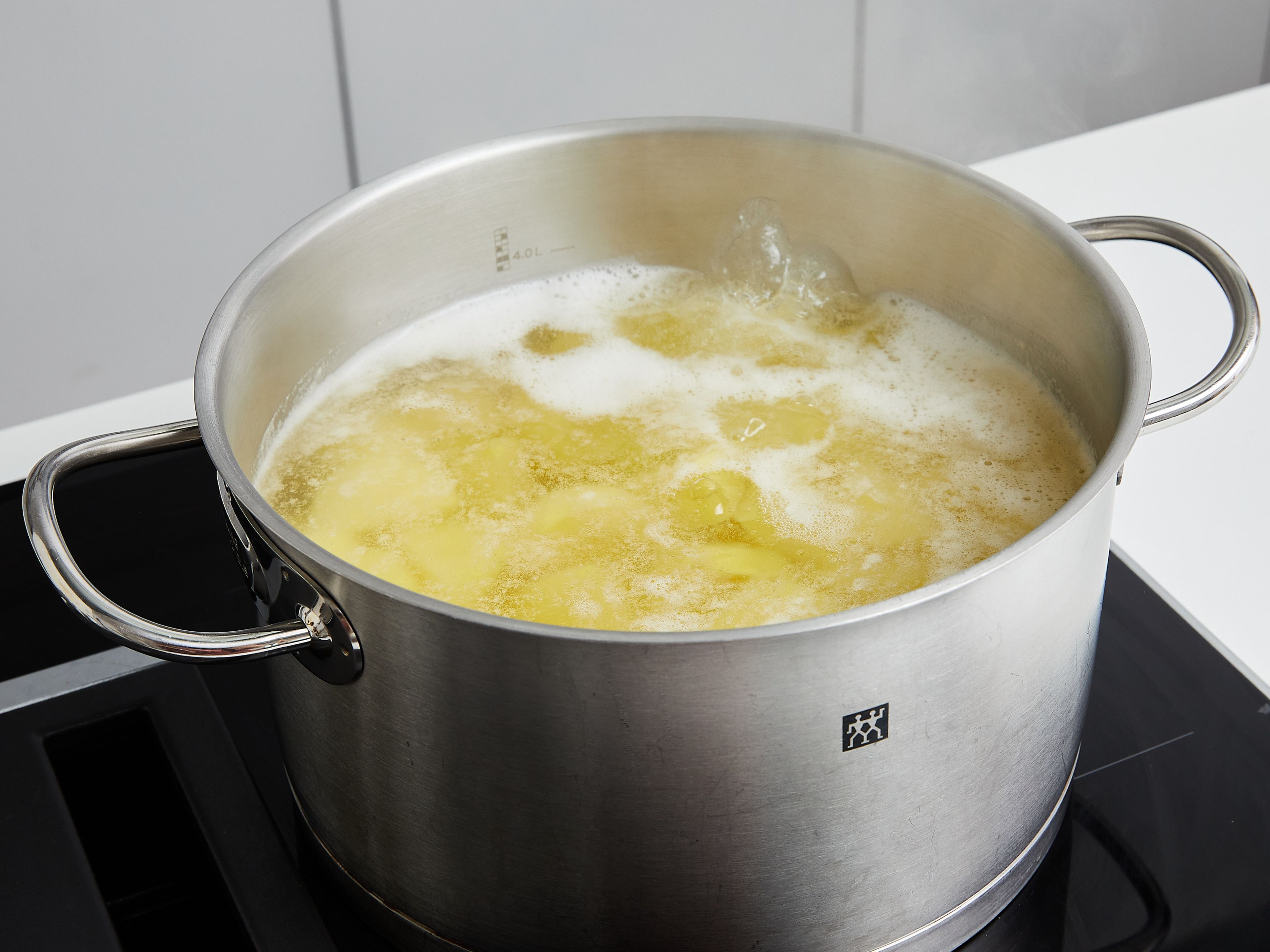 Den Ofen auf 220°C Ober-Unterhitze (200°C Umluft) vorheizen. Kartoffeln schälen und in große Stücke schneiden, ca. 4–5 cm groß. Bringe 2 l Wasser in einem großen Topf bei starker Hitze zum Kochen. Salz, Backpulver und Kartoffeln hinzufügen. Umrühren, damit sie sich verbinden. Erneut zum Kochen bringen, Hitze auf ein Köcheln reduzieren und ca. 10 Min. kochen, oder bis die Kartoffeln beim Einstechen mit einem Messer kaum noch Widerstand bieten.
