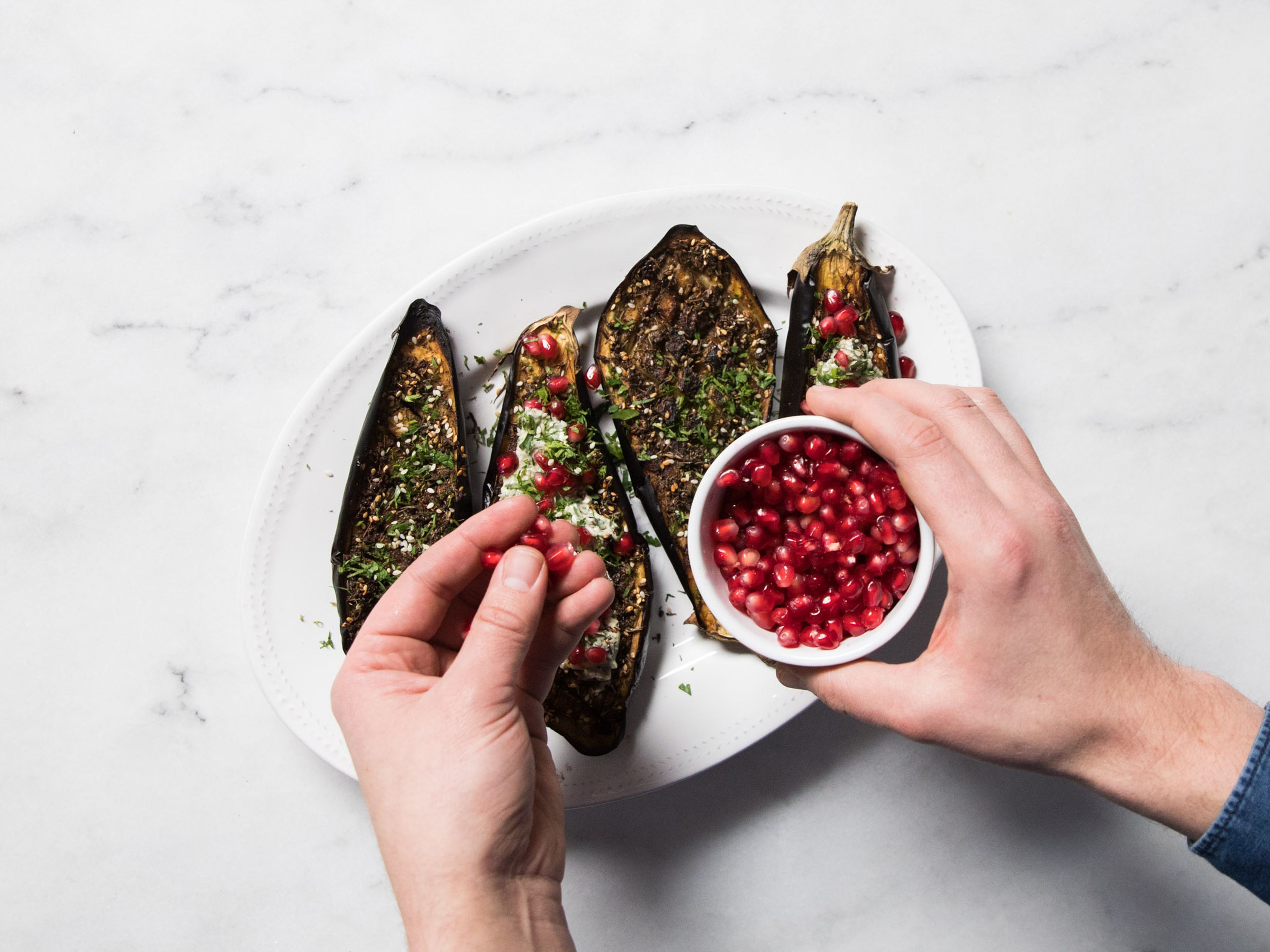 Remove roasted eggplants from the oven and serve with tahini dip. Garnish with pomegranate seeds, fresh parsley, mint, and sesame seeds. Enjoy!