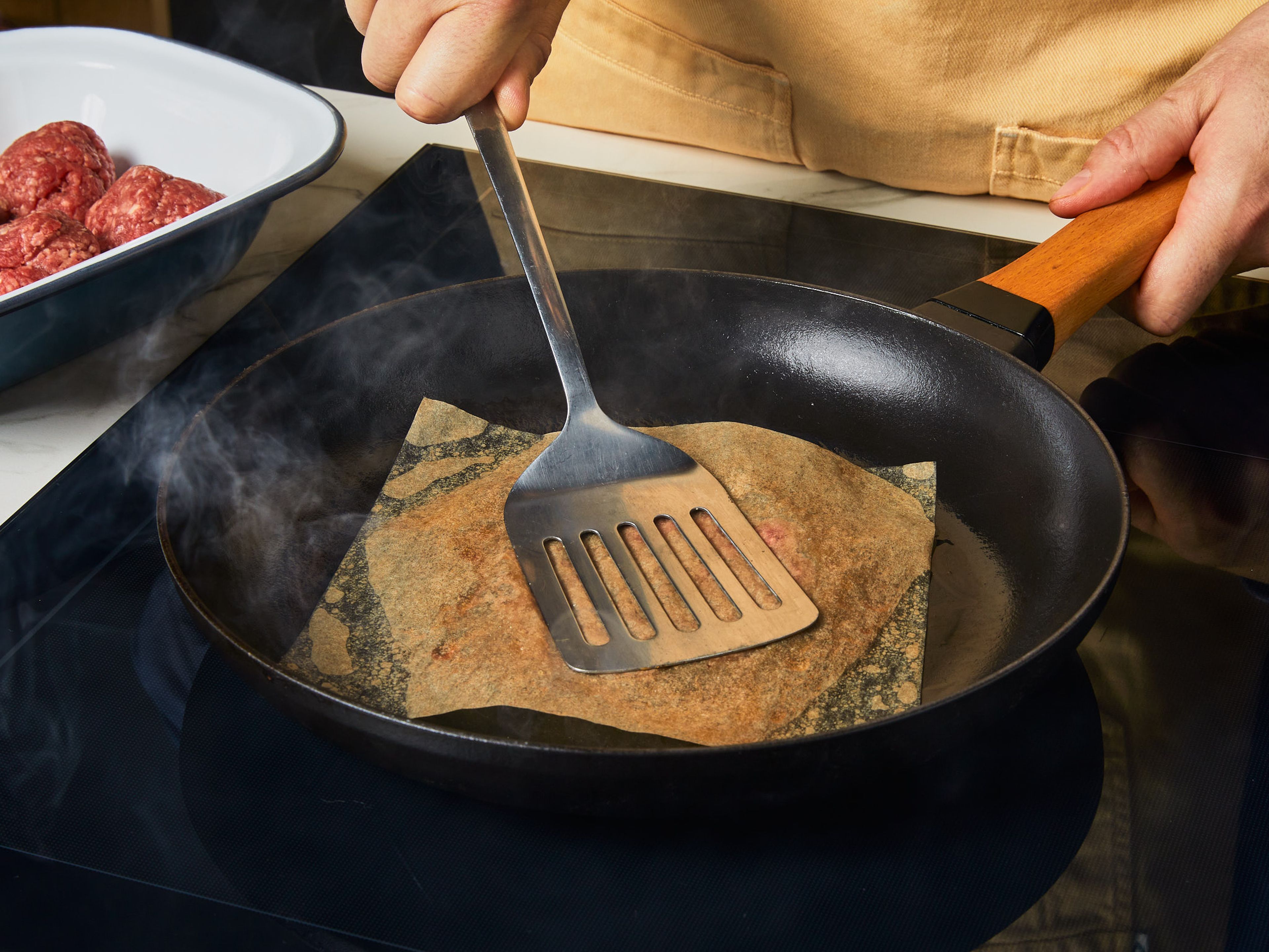 Eine gusseiserne Pfanne auf hoher Stufe erhitzen, dann leicht mit Pflanzenöl einpinseln. Das Rinderhackfleisch in gleich große Portionen teilen und zu lockeren Kugeln formen. Die Kugeln portionsweise in die Pfanne geben, dabei darauf achten, dass diese nicht zu voll wird. Jede Kugel mit einem Stück Backpapier abdecken und mit einem Pfannenwender flachdrücken, bis sie ca. 1 cm dick sind. Mit Salz und Pfeffer würzen und bei starker Hitze ca. 2 Min. braten, bis die Ränder knusprig und braun sind.