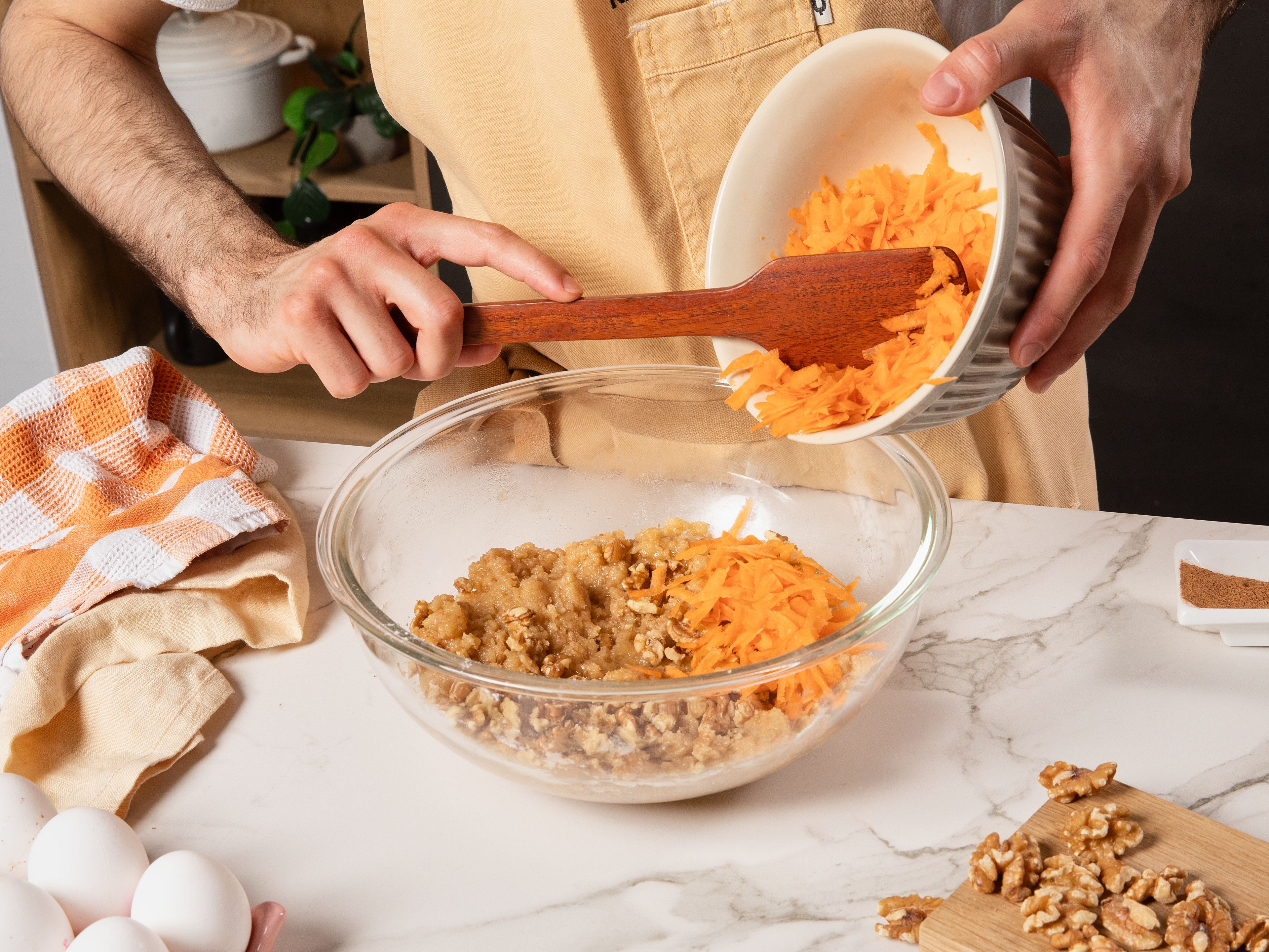 Backofen auf 170 °C vorheizen. In einer Rührschüssel Mehl und Natron sieben, dann Zucker, Zimt und Salz dazugeben und gut vermengen. Öl und Ei hinzufügen und erneut gut verrühren. Karotten fein raspeln, Walnüsse grob hacken und alles unter den Teig mischen. Dann beiseitestellen.
