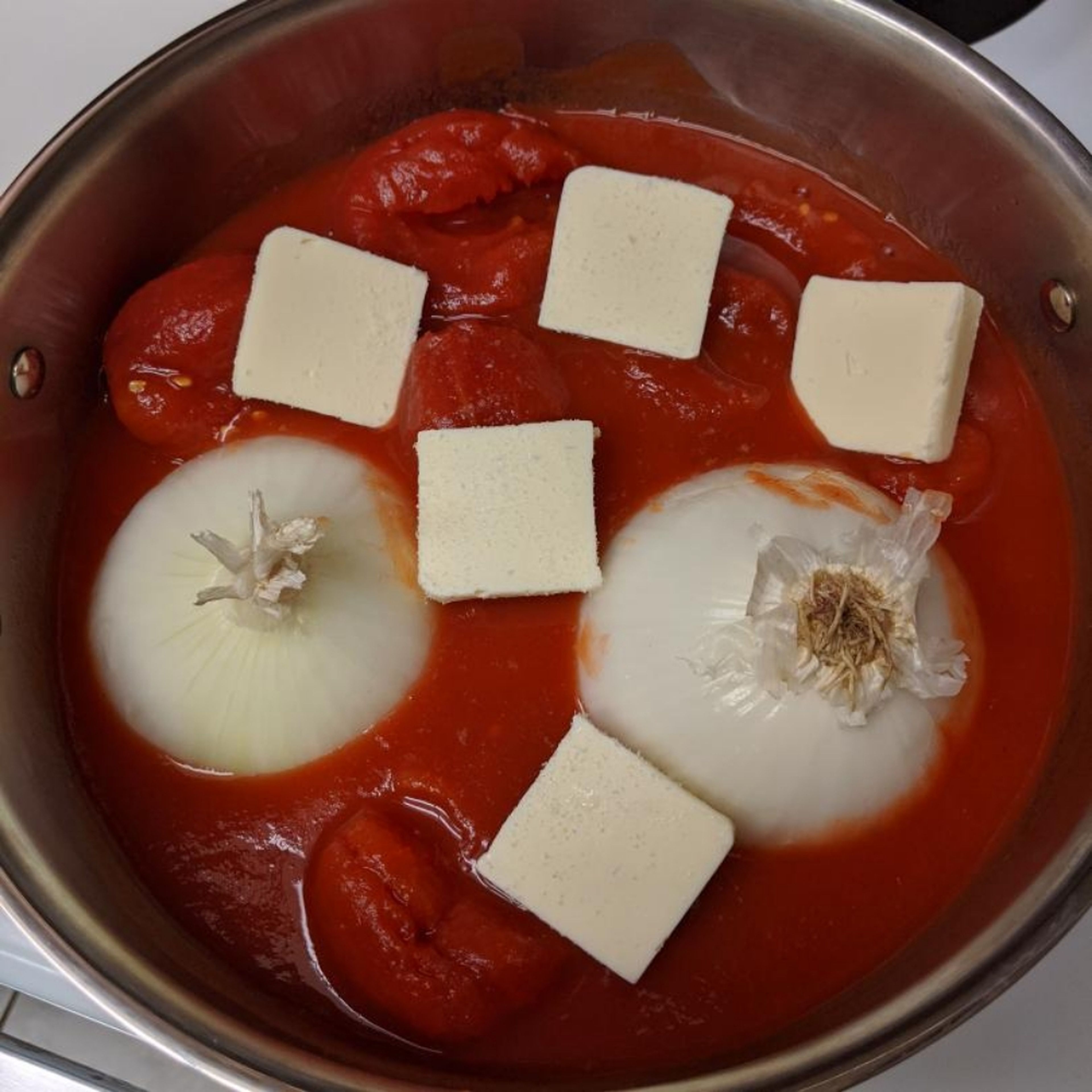 Empty tomatoes into sauce pan, cut onion in half and place cut side down into pan, slice up the butter and place it around the sauce, sprinkle a pinch of salt over everything. Bring to a simmer over medium-high heat.