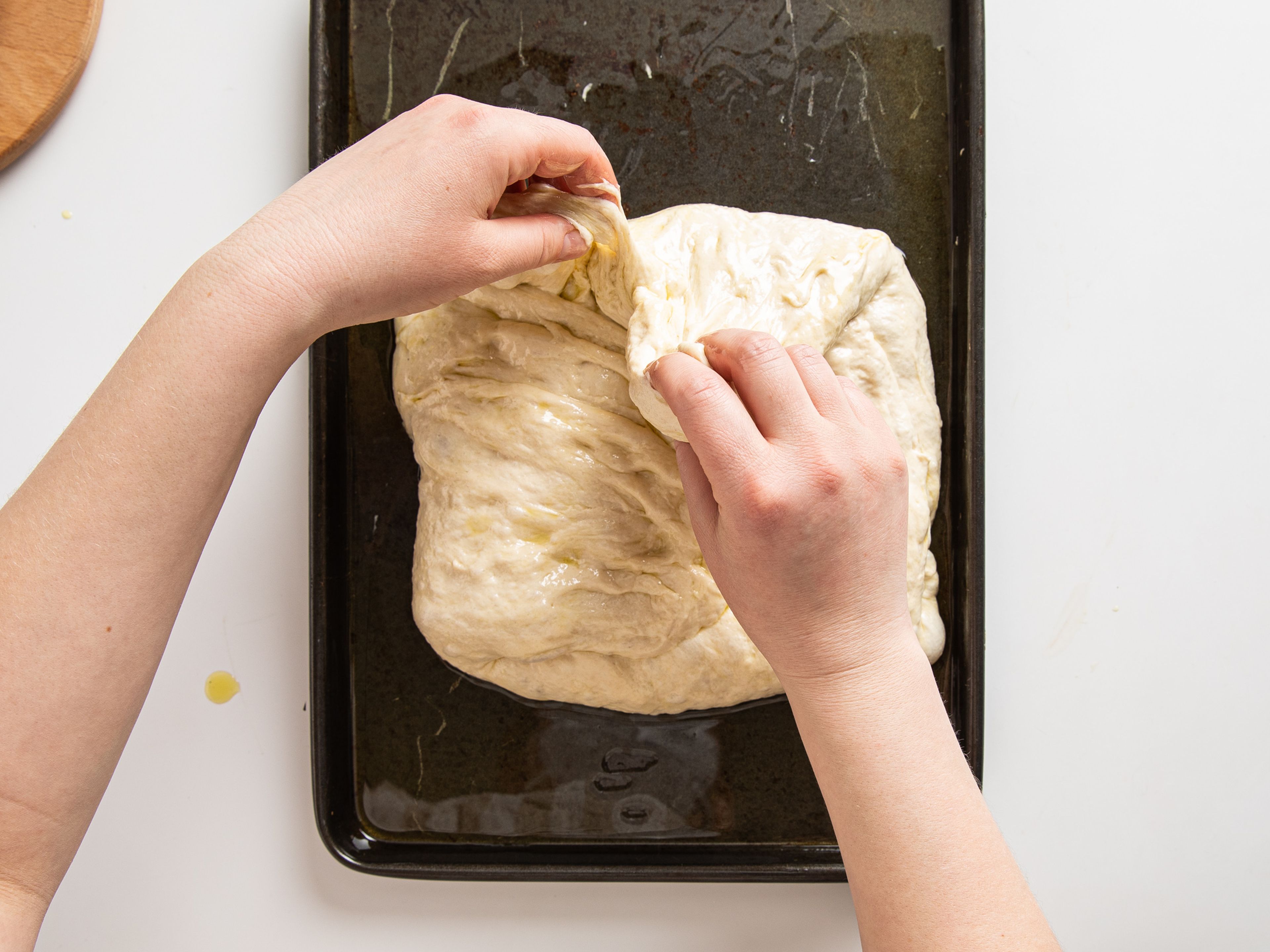 Drizzle oil onto a rimmed baking sheet and spread it around to coat the entire inside of the sheet pan. Transfer dough into it, and fold each of the edges in to the middle of the dough to trap some air. Let it relax for a moment and gently push it out to fit the tray. Leave to rest for 1 hr at room temperature.