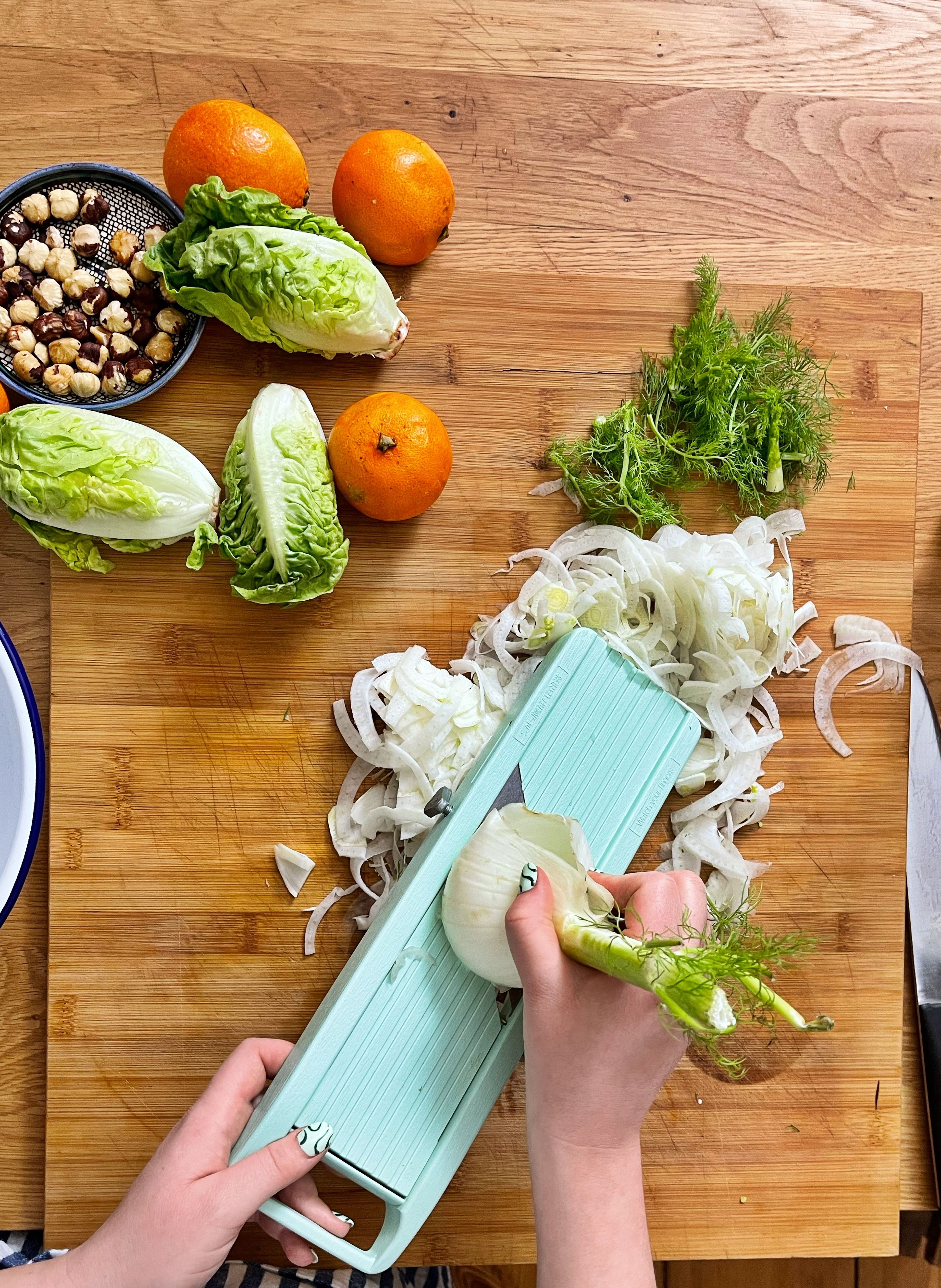 Zuerst den Fenchel mit dem Gemüsehobel in sehr feine Streifen hobeln. Das Grün kannst du aufheben, damit garnieren wir später den Salat.