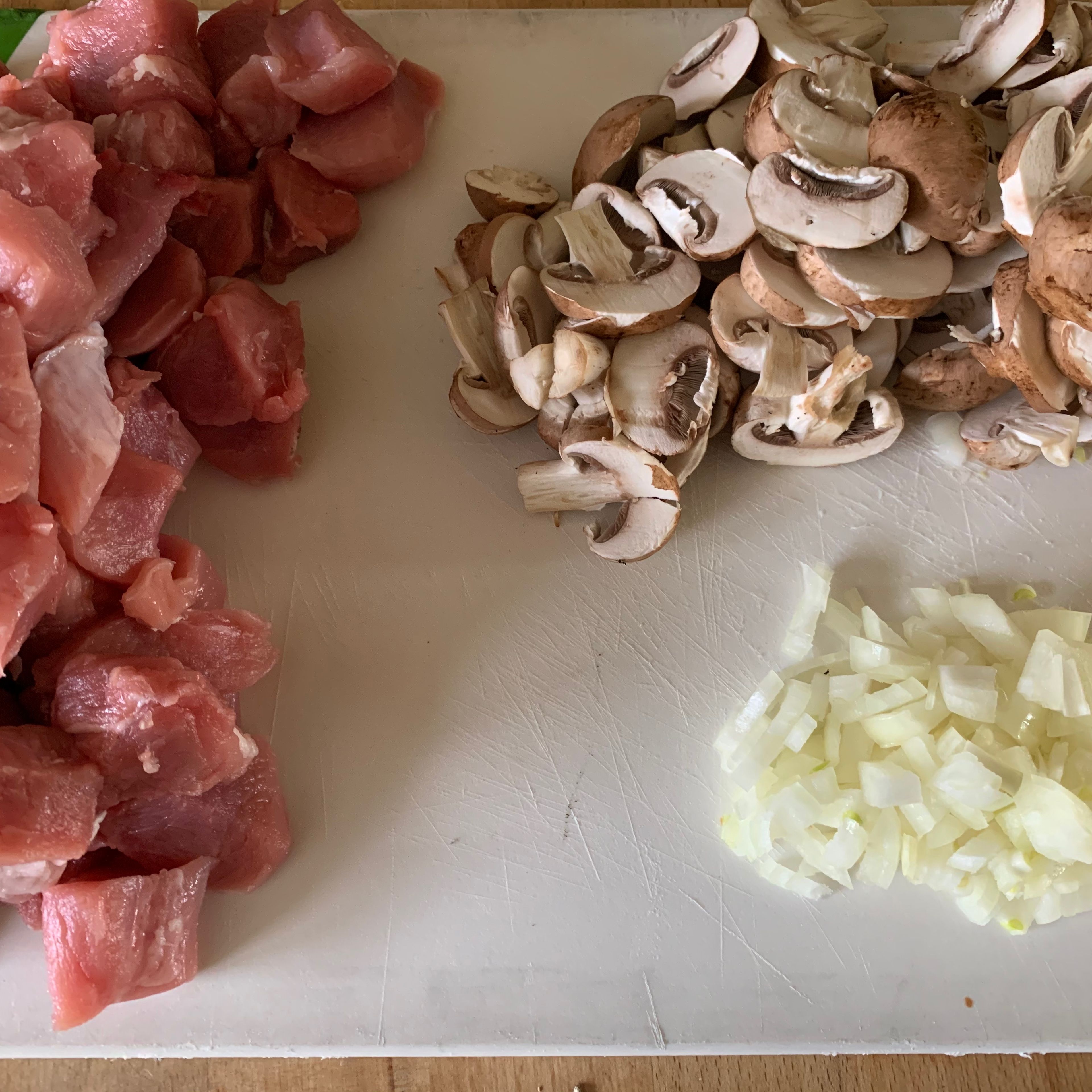 Das Fleisch in 3-4 cm große Würfel schneiden. Die Zwiebeln klein würfeln und die Champignons in Scheiben schneiden.