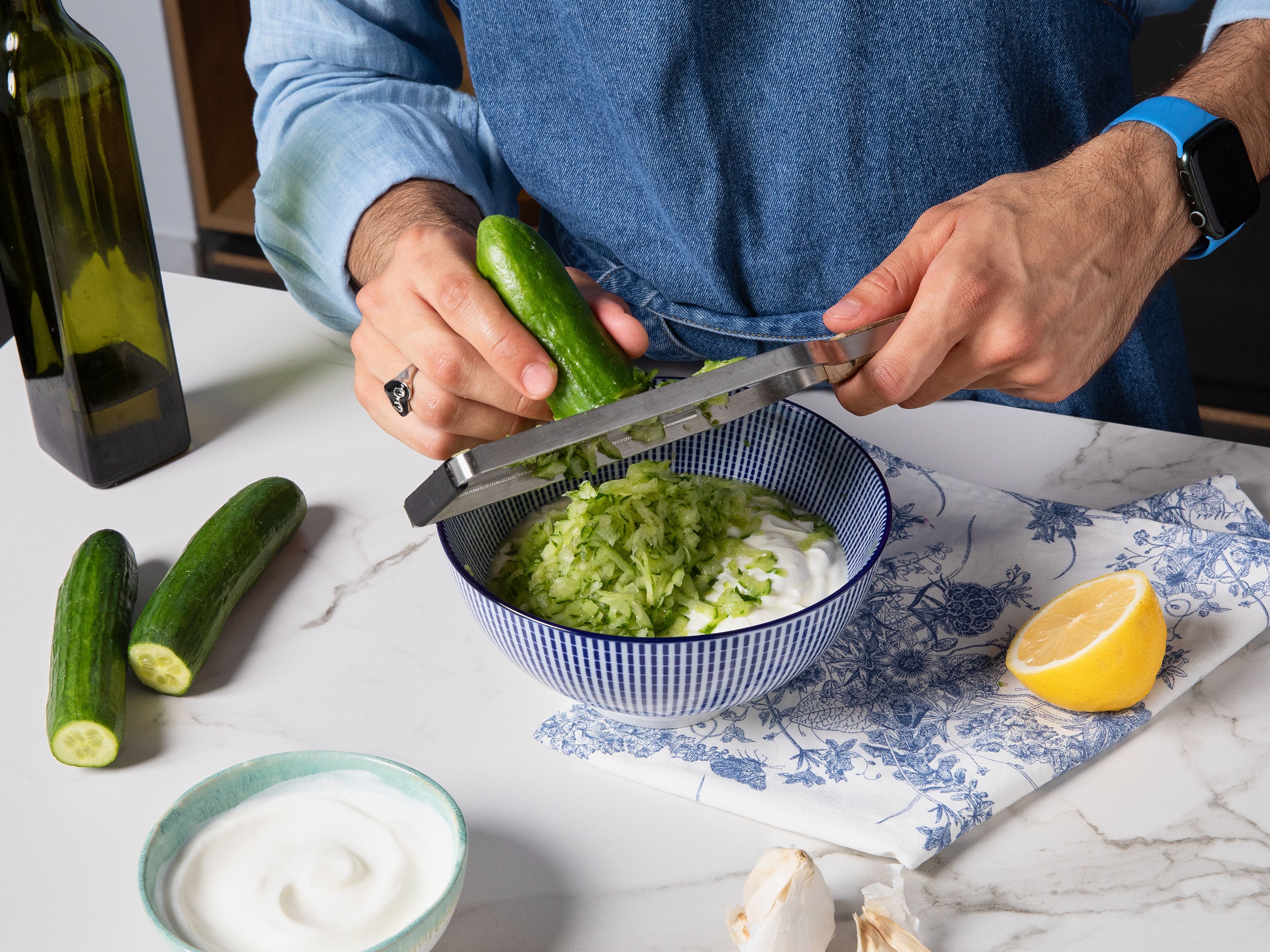 While the orzo cooks, start making the tzatziki and grate half the cucumber into a bowl. To the same bowl, add greek yogurt, rest of finely minced garlic, olive oil, lemon juice, and salt. Mix until it’s creamy and well combined. For the rest of the bowl, slice remaining cucumber and halve cherry tomatoes. Cut the remaining onion half into thin rings.