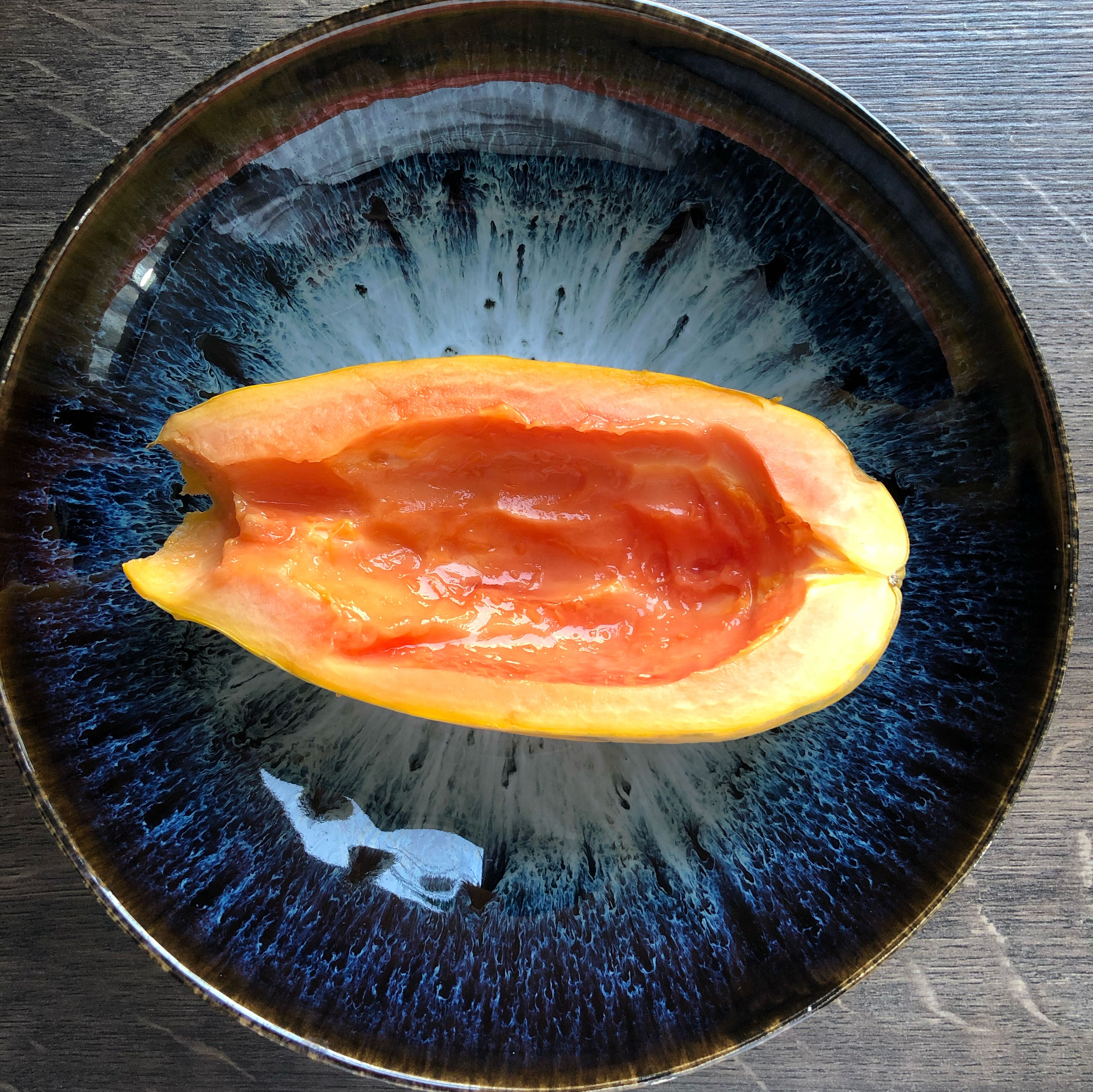 Die Papaya halbieren und entkernen, anschließend jede Hälfte auf einen Teller legen.