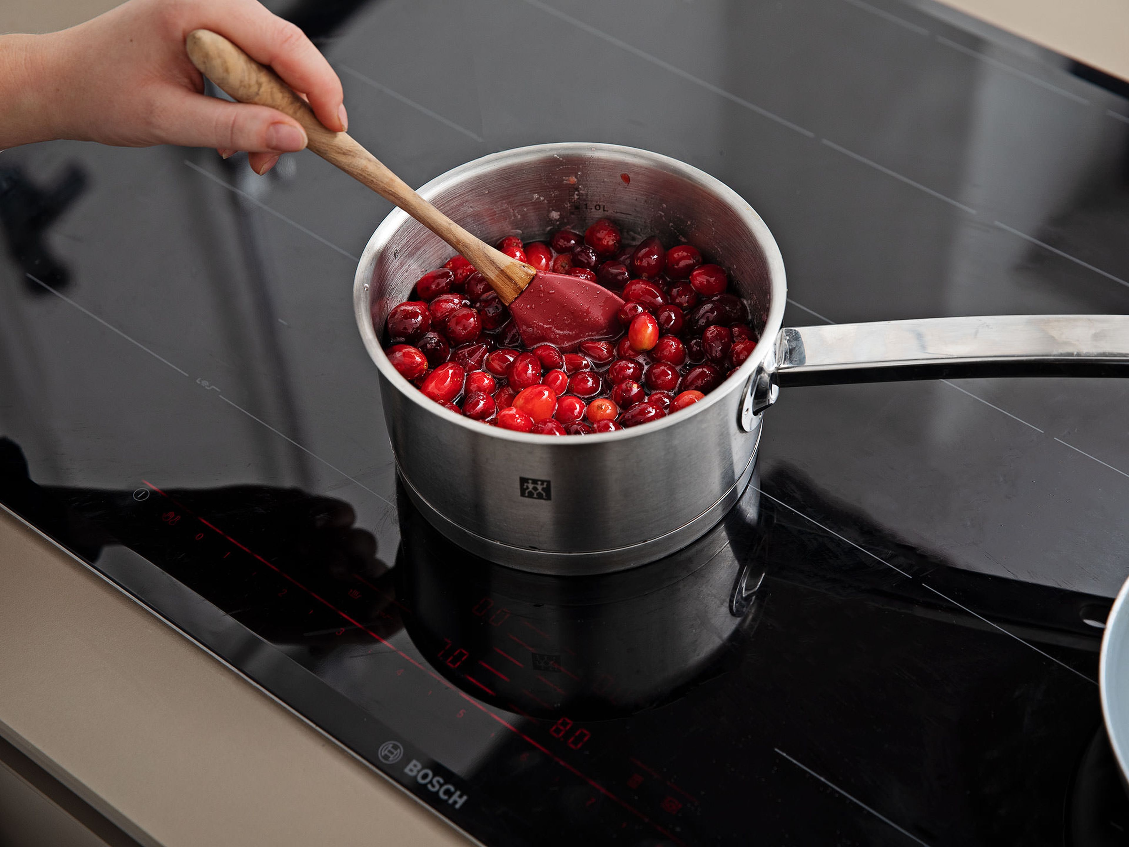 Backofen auf 220°C vorheizen. Für die Cranberryfüllung Vanilleschote längs halbieren, das Mark auskratzen und in einen Topf geben. Cranberrys, einen weiteren Teil des Zuckers, Vanillepuddingpulver, Speisestärke und das übrige Wasser zugeben. Kurz aufkochen lassen, dann Hitze reduzieren und für ca. 20 Min. einköcheln lassen. Zum Abkühlen beiseitestellen, anschließend glatt pürieren.