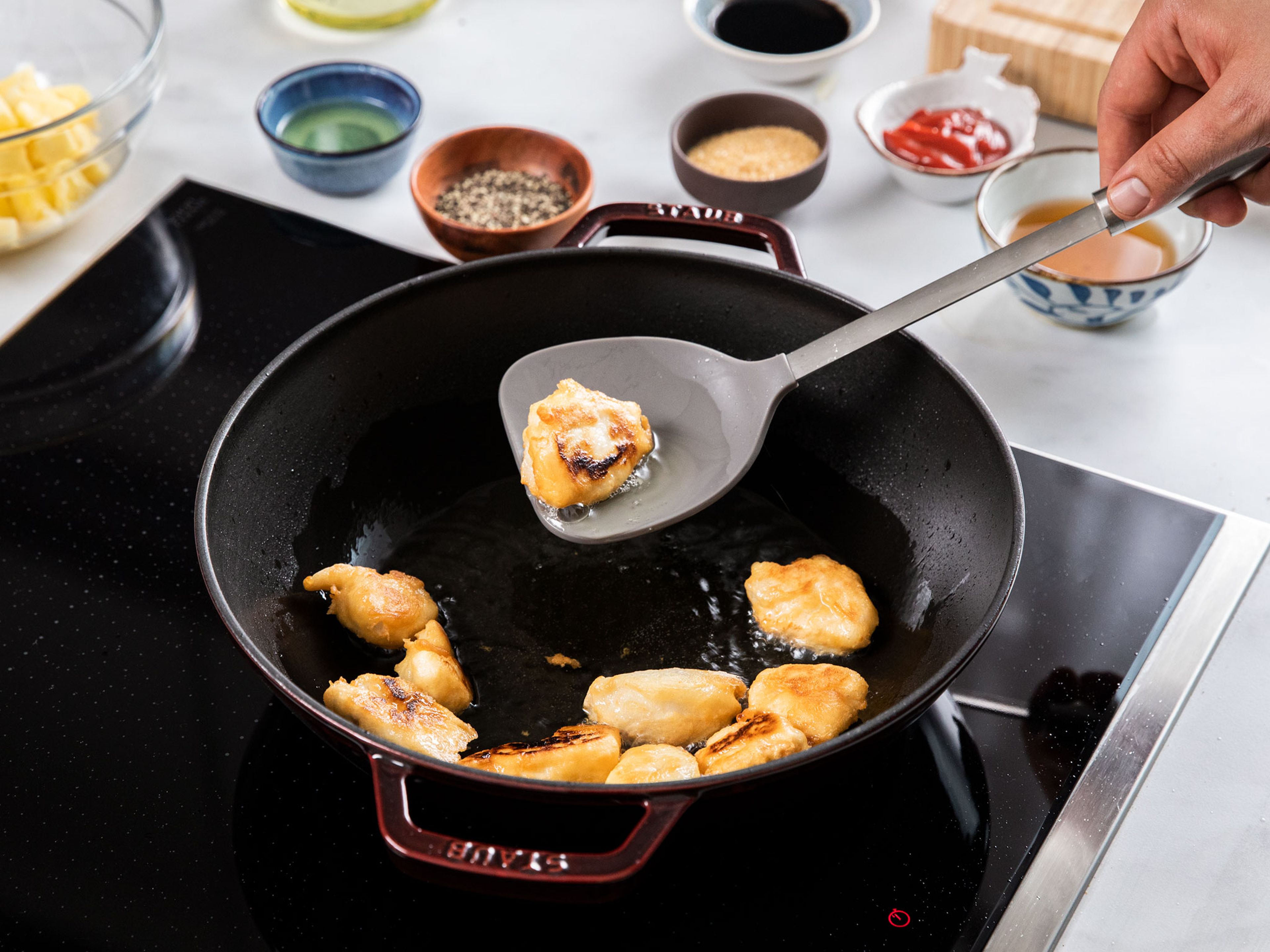 To make the tempura batter, add flour, baking powder, starch, salt, a quarter of the sunflower oil, and water to a bowl. Whisk to combine. Add chicken and toss to coat. Heat remaining sunflower oil in a wok over 170°C/340°F, add chicken, and deep fry in batches until golden brown on both sides. Transfer fried chicken to a paper towel-lined plate to drain.