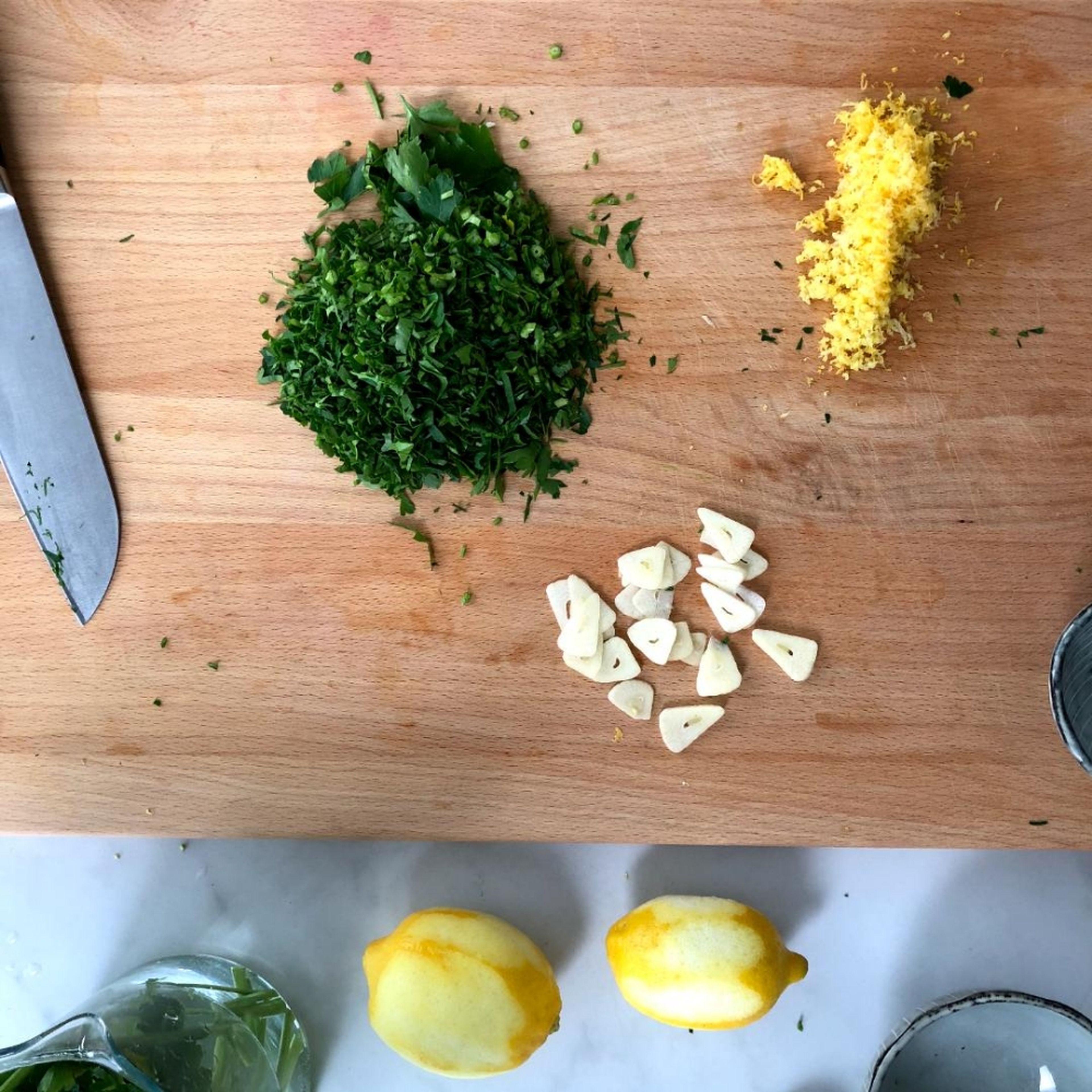 In the meantime, slice the remaining two cloves of garlic. Finely chop the parsley with stems. Grate the zest from the lemons.