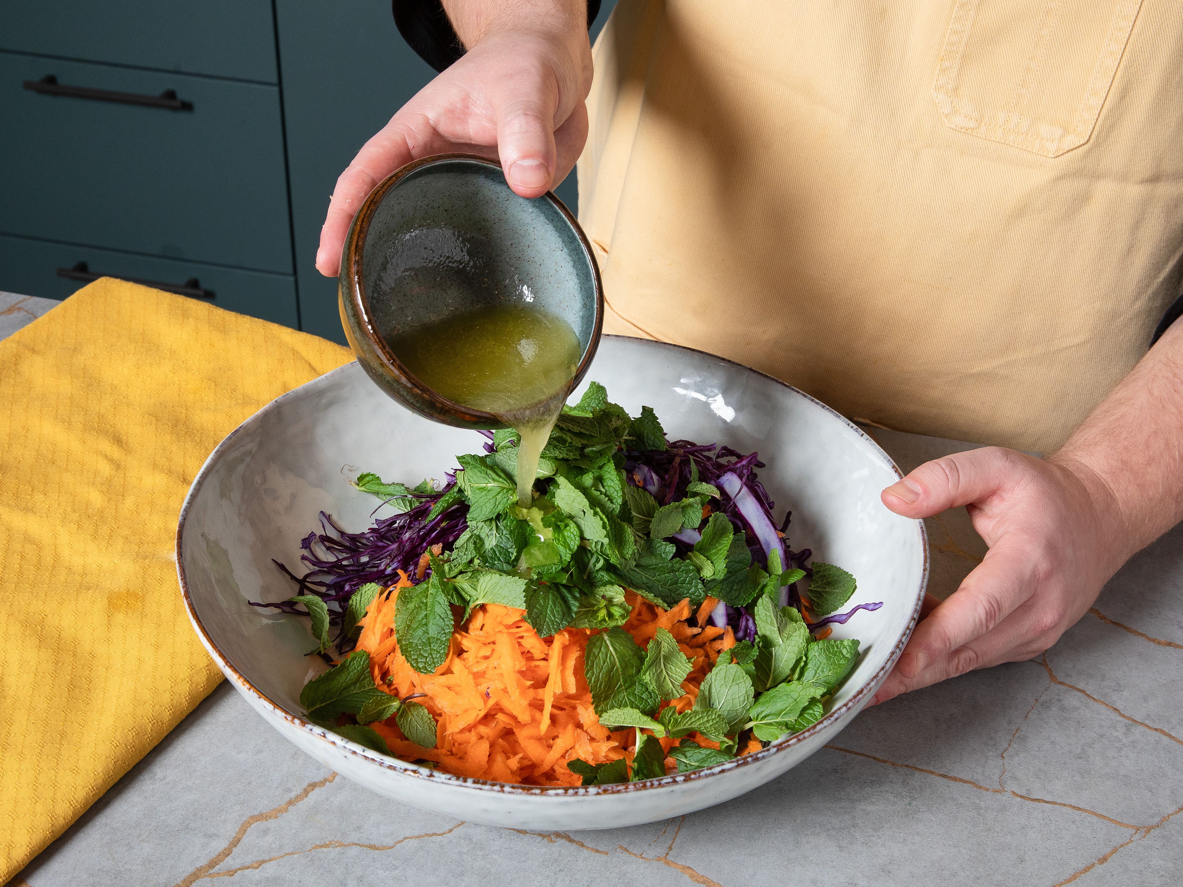 Das Dressing über den Kohl geben und mit Handschuhen gut einmassieren. Die Stiele der Minze entfernen, die Blätter fein hacken und unter den Coleslaw mischen. Nach Belieben mit Limettenspalten und Minzblättern garnieren und sofort servieren.