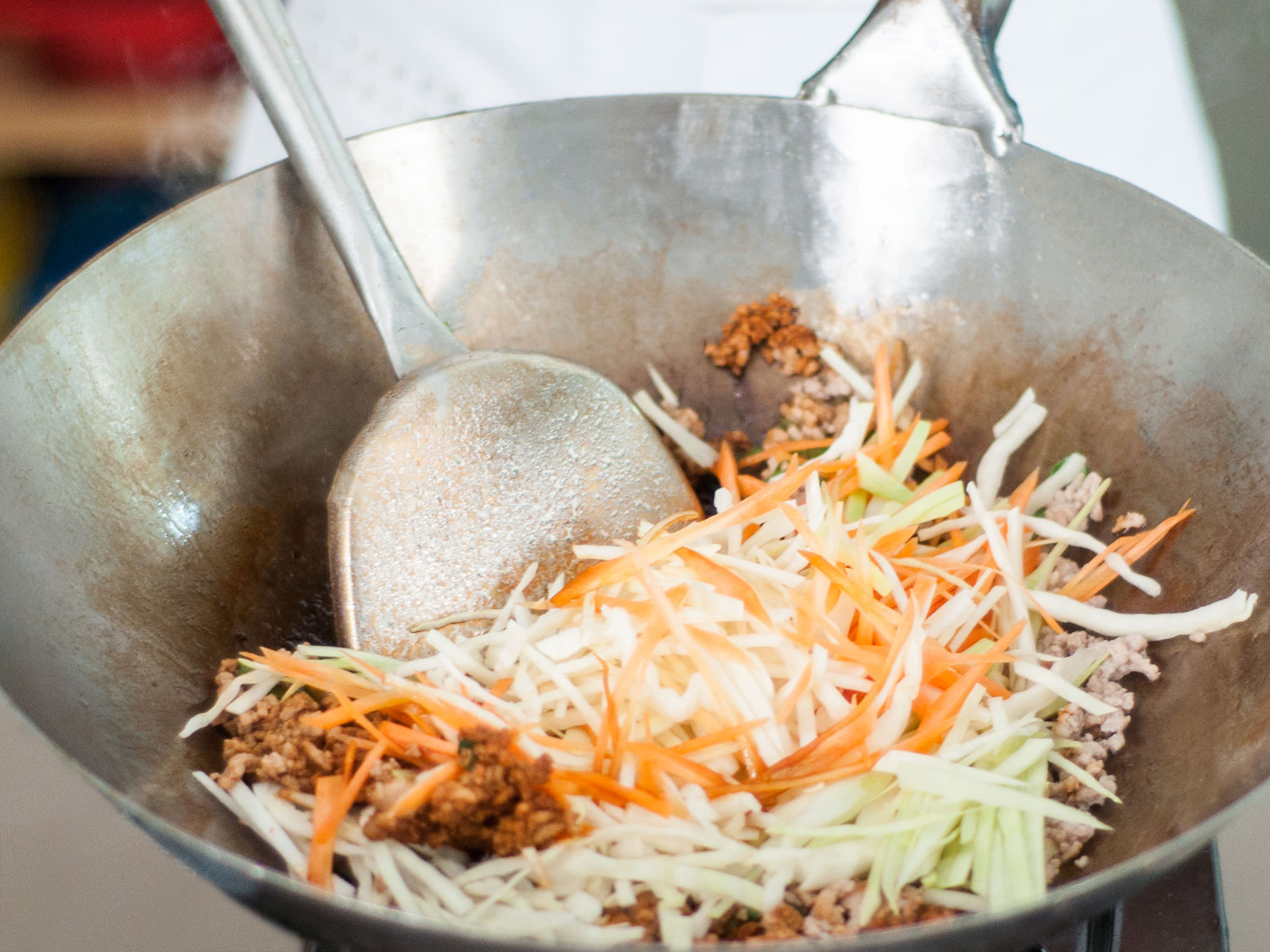 Add oil to a wok and fry ground pork for approx. 2 – 3 min. until browned. Add carrots and white cabbage and cook on low heat until softened for approx. 6 – 7 min. . Add sliced ginger, garlic, and green onions.  Season with five spice powder, salt, pepper, and dark soy sauce to taste.