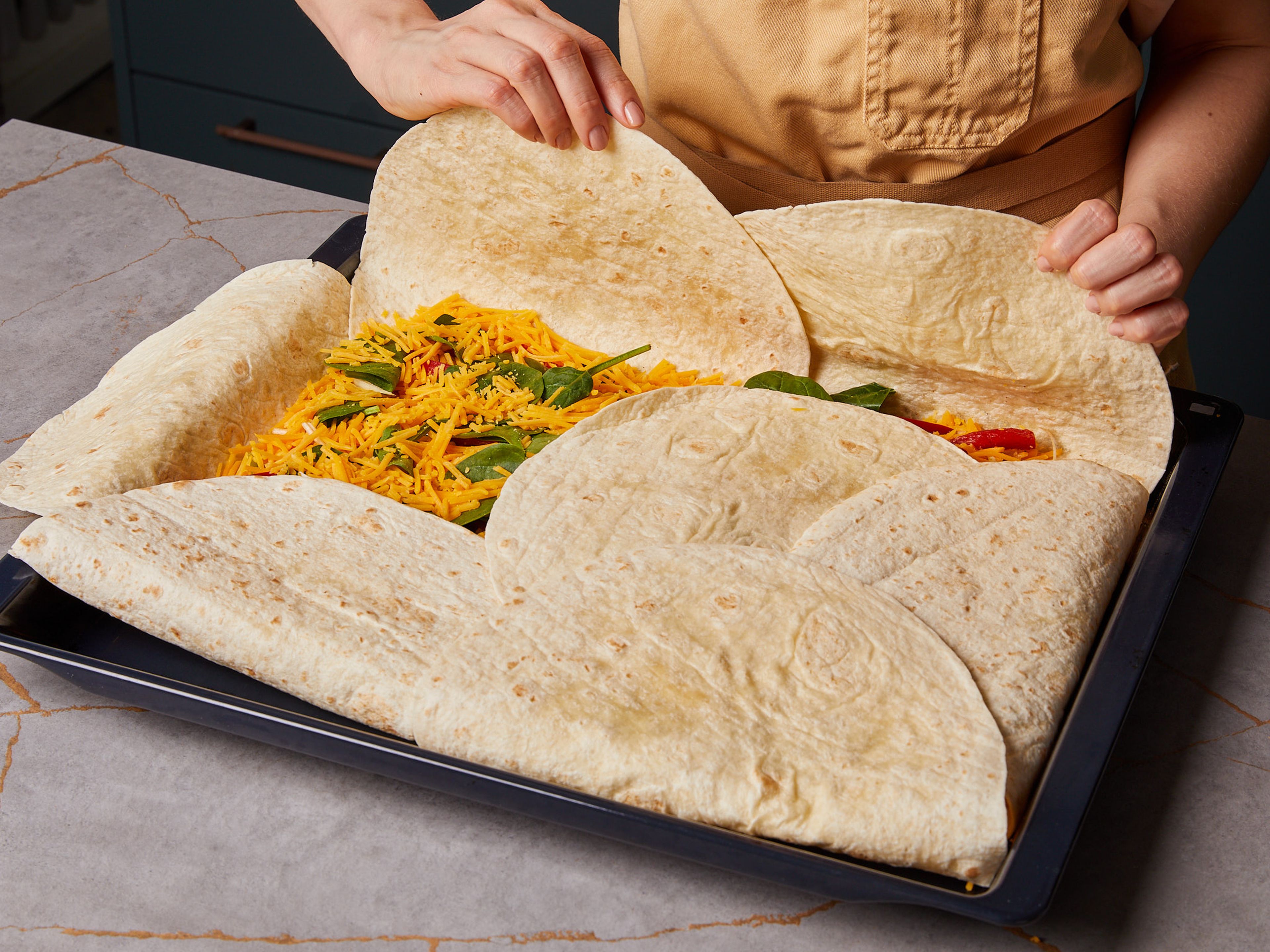 Cover the middle part with the remaining tortillas and fold the tortillas on the sides over the filling to fully cover the top. Place a second baking sheet or two baking forms on top to weigh it down.