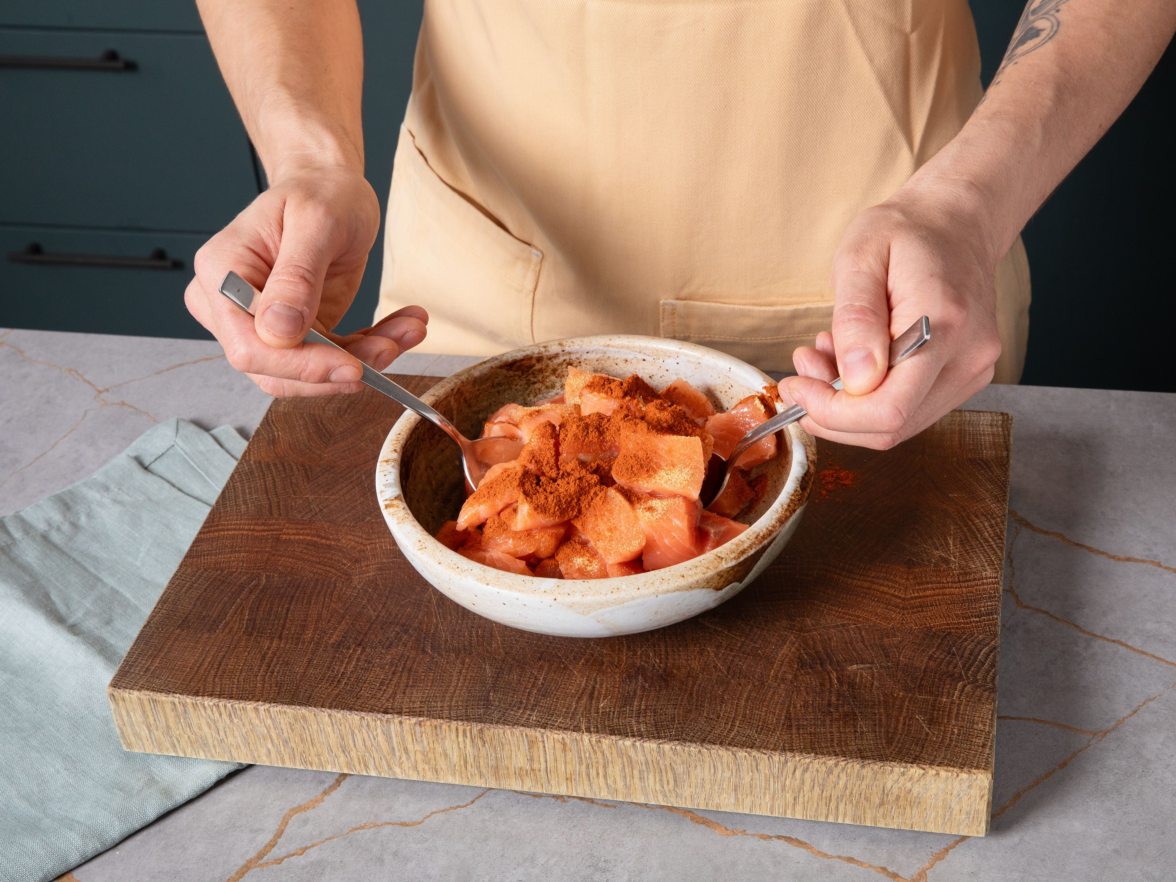 Den Ofen auf 200 °C Ober-/Unterhitze vorheizen. In einer großen Schüssel Mayonnaise, süße Chilisauce und Sriracha verrühren und beiseitestellen. Den Lachs in mundgerechte Stücke schneiden, in einer Schüssel mit Paprikapulver, Knoblauchpulver, Salz und Pfeffer würzen und gut vermengen.