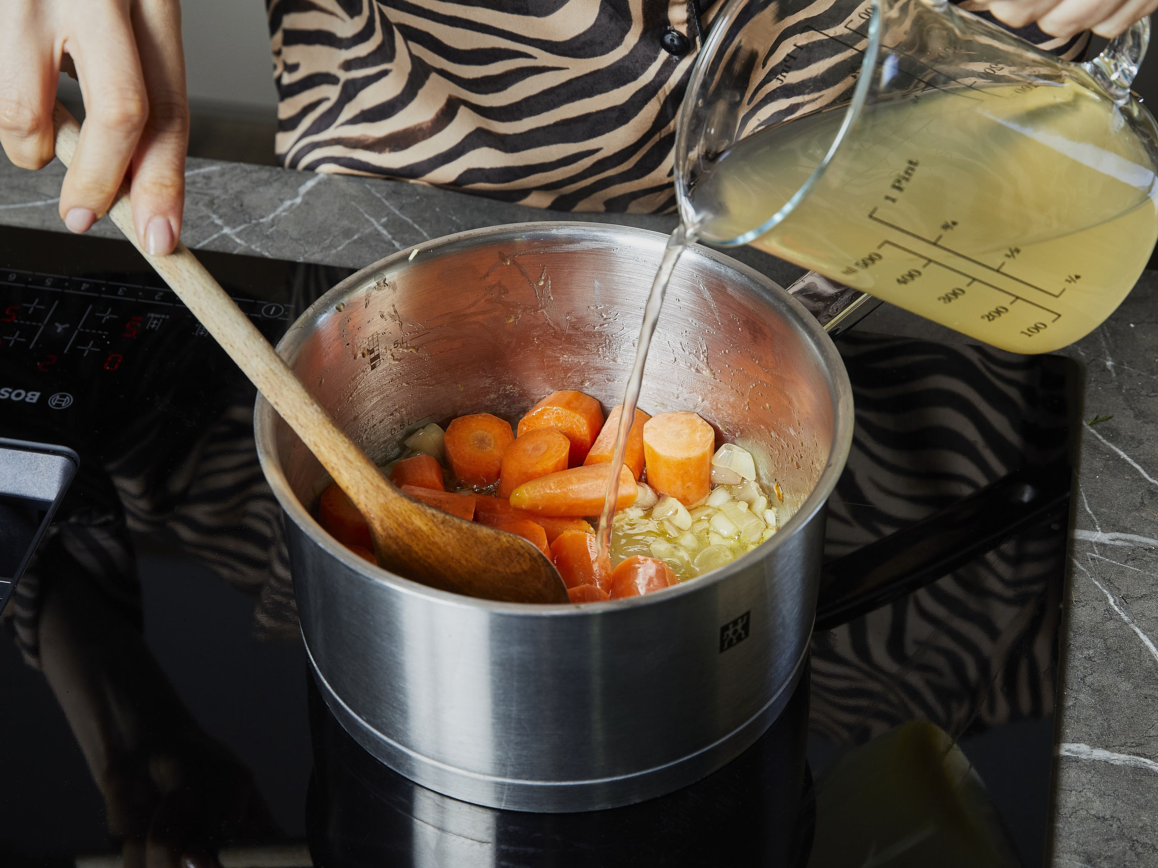 In einem mittelgroßen Topf Butter bei mittlerer Hitze schmelzen. Schalotten und ⅔ des Knoblauchs darin unter häufigem Rühren ca. 3 Min. goldgelb anbraten. Karotten zugeben, kurz anbraten, dann mit Gemüsebrühe ablöschen. Zum Kochen bringen, dann den Topf abdecken, die Hitze reduzieren und ca. 10 Min. köcheln lassen, bis die Karotten gabelzart sind. In der Zwischenzeit die Nudeln in das kochende Wasser geben und nach Packungsanweisung bissfest kochen. Etwa 250 ml/1 Tasse des Nudelwassers aufbewahren, bevor die Nudeln abgegossen werden, und die Nudeln anschließend wieder in den großen Topf geben.