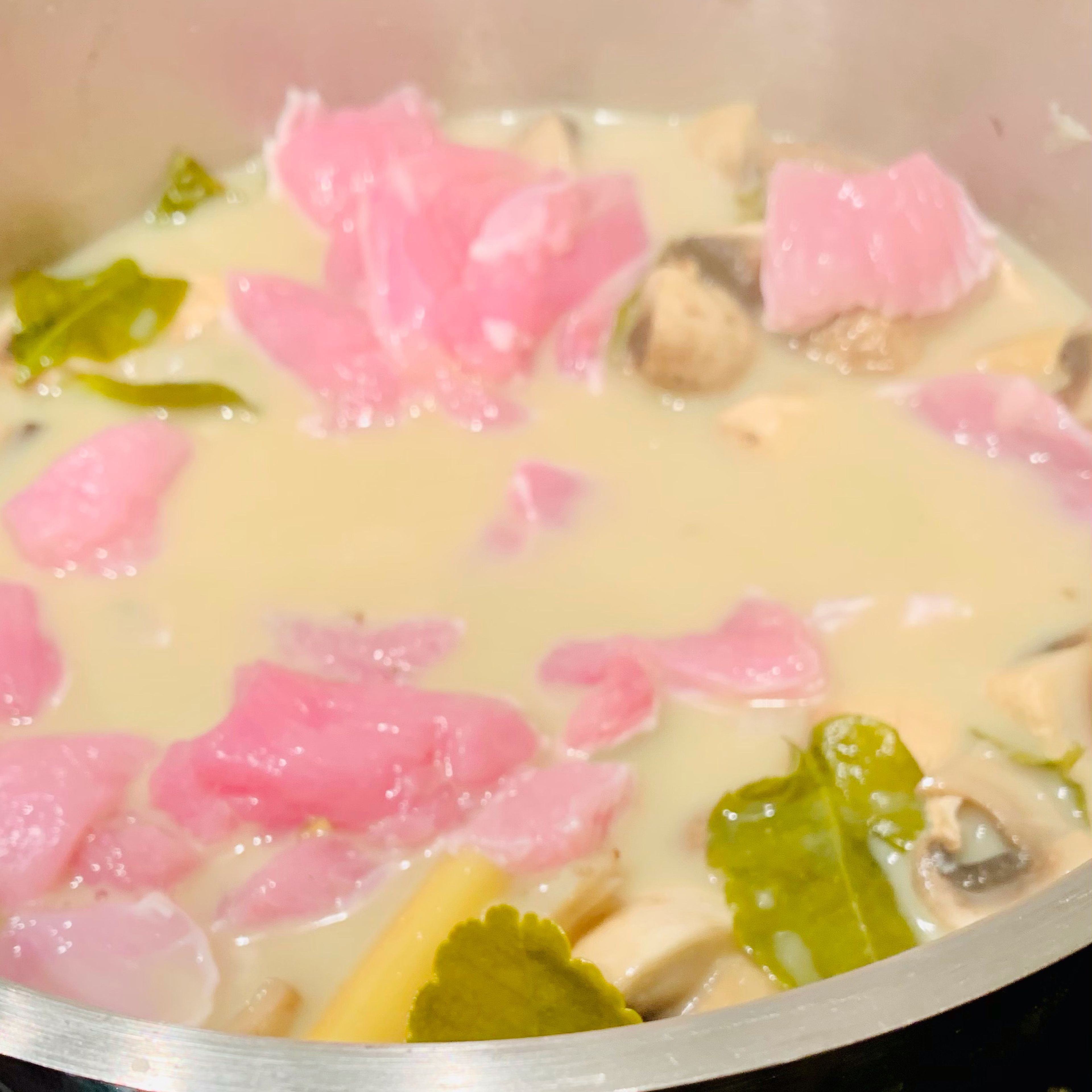 Hitze runtersetzen, klein geschnittenes Hähnchenfleisch und restliche Kokosmilch hinzufügen und einige Minuten ziehen lassen. Mit Fischsauce abschmecken, in Teller umfüllen und mit Koriander dekorieren.