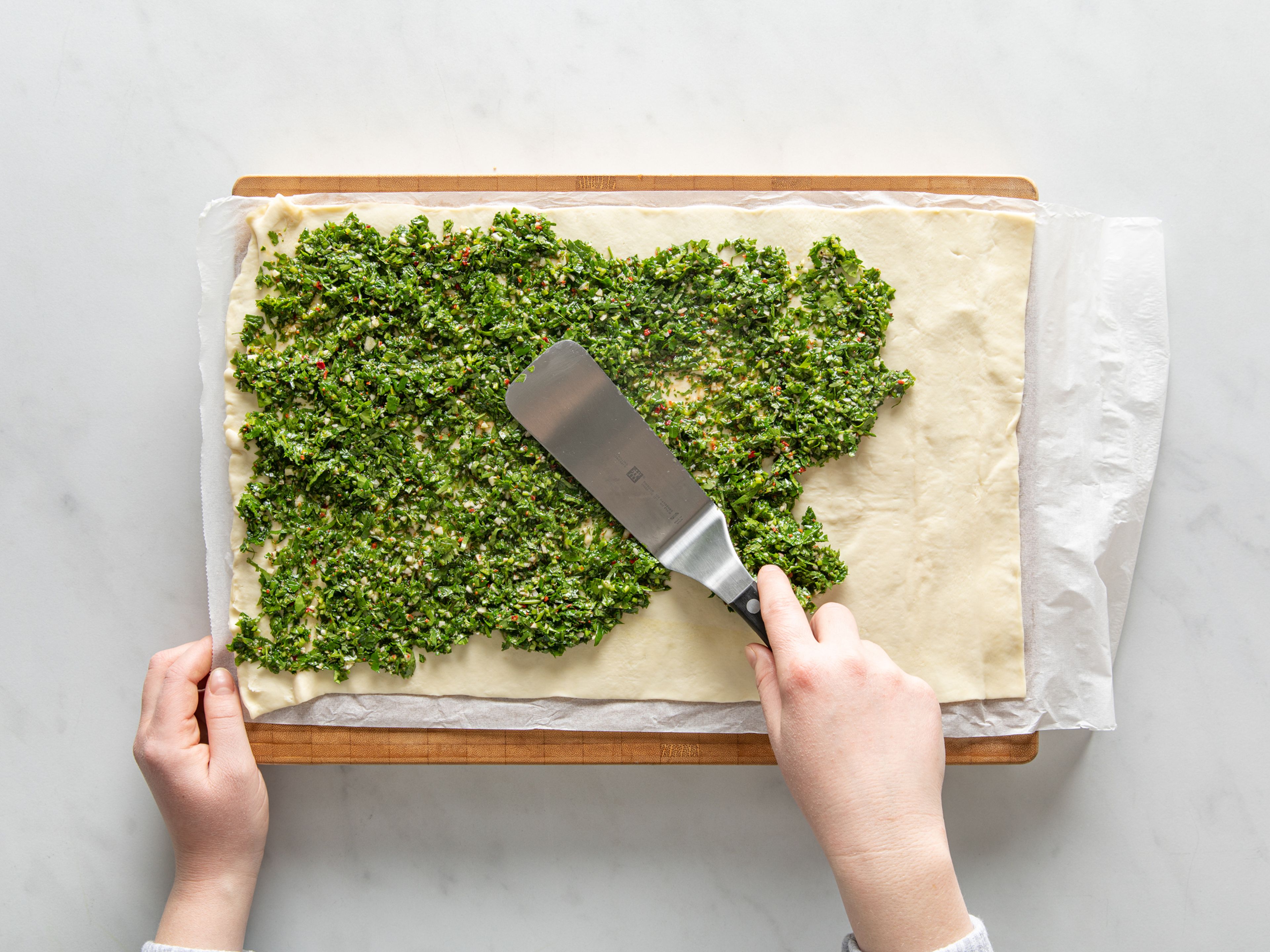Lay out the puff pastry on a floured work surface. Spread chimichurri evenly over the top, leaving a 2.5 cm-wide strip along the top edge, untouched. Grate cheddar over everything and sprinkle with olives and chopped onion. Roll pastry into a tight log, then cut into 4 cm-wide discs.