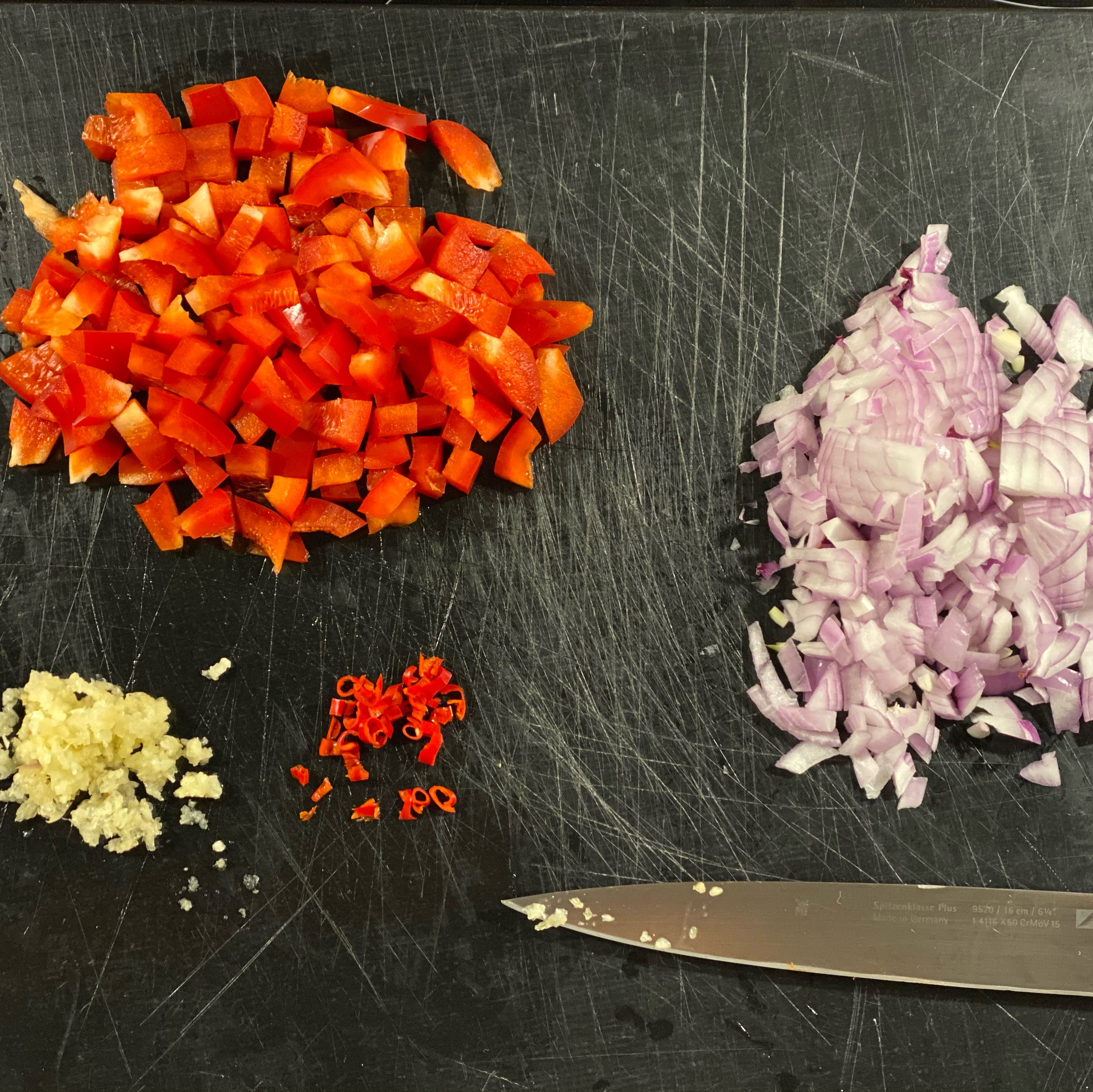 Zwiebel, Chili und Paprika klein schneiden. Knoblauch fein hacken.