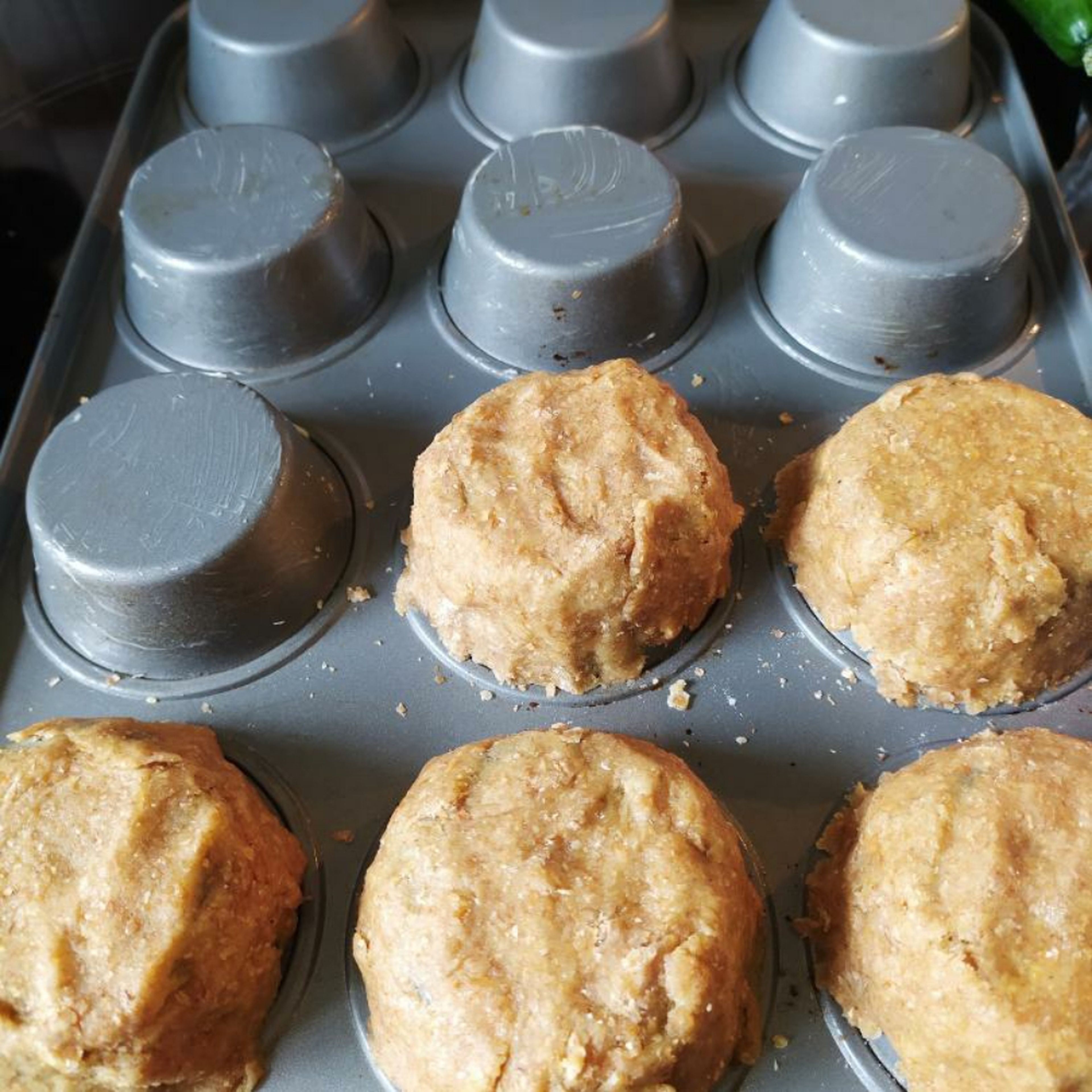 Das Muffinblech umdrehen und einfetten. Den Teig ausrollen und um die Muffinformen legen. Das Blech in den Ofen schieben und diesen auf 200° einschalten. Teig 15 Minuten vorbacken.