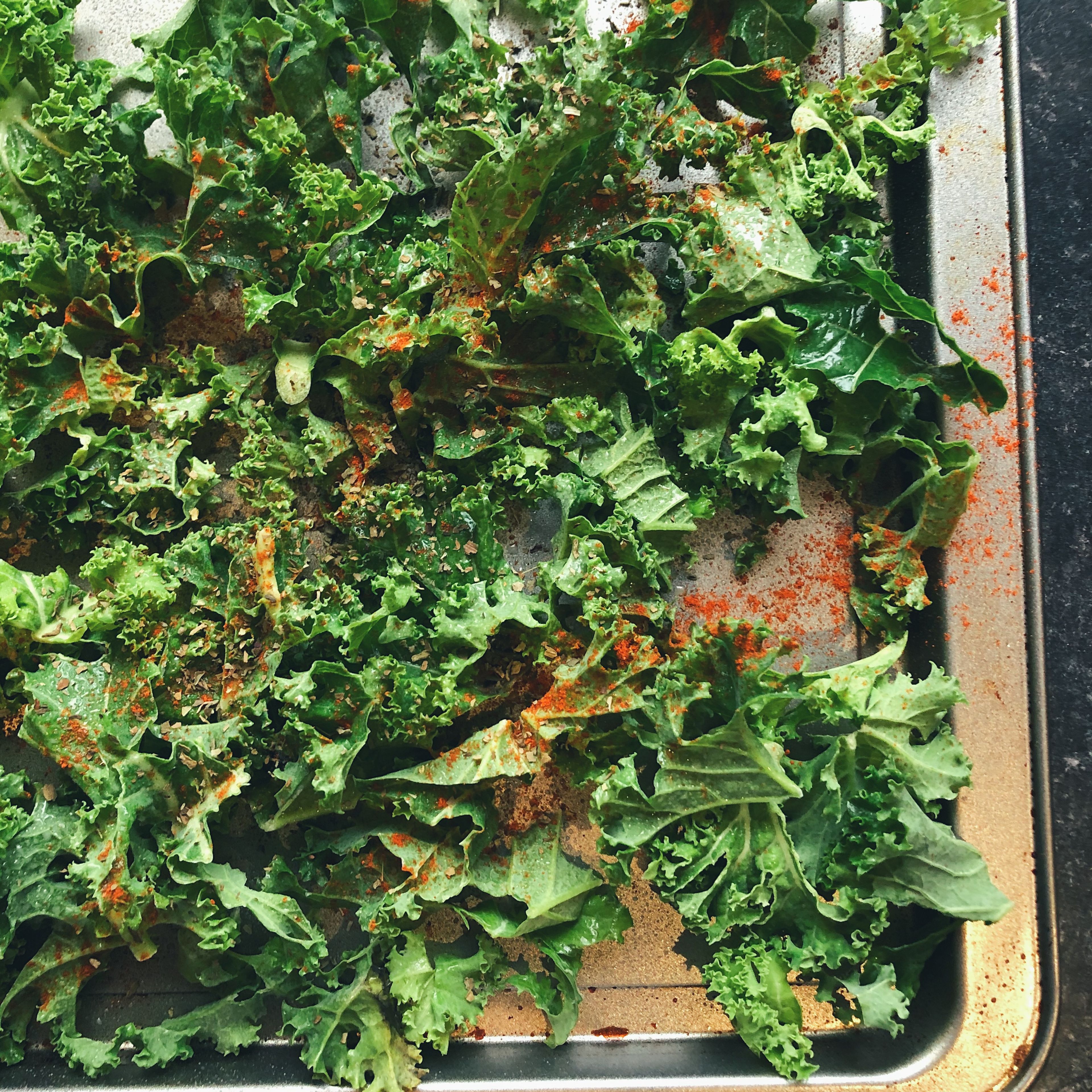 Lay kale on baking tray. Sprinkle basil, paprika, Salt and pepper evenly over the top and cover lightly with olive oil. Bake in oven for 10 minutes at 200 degrees.