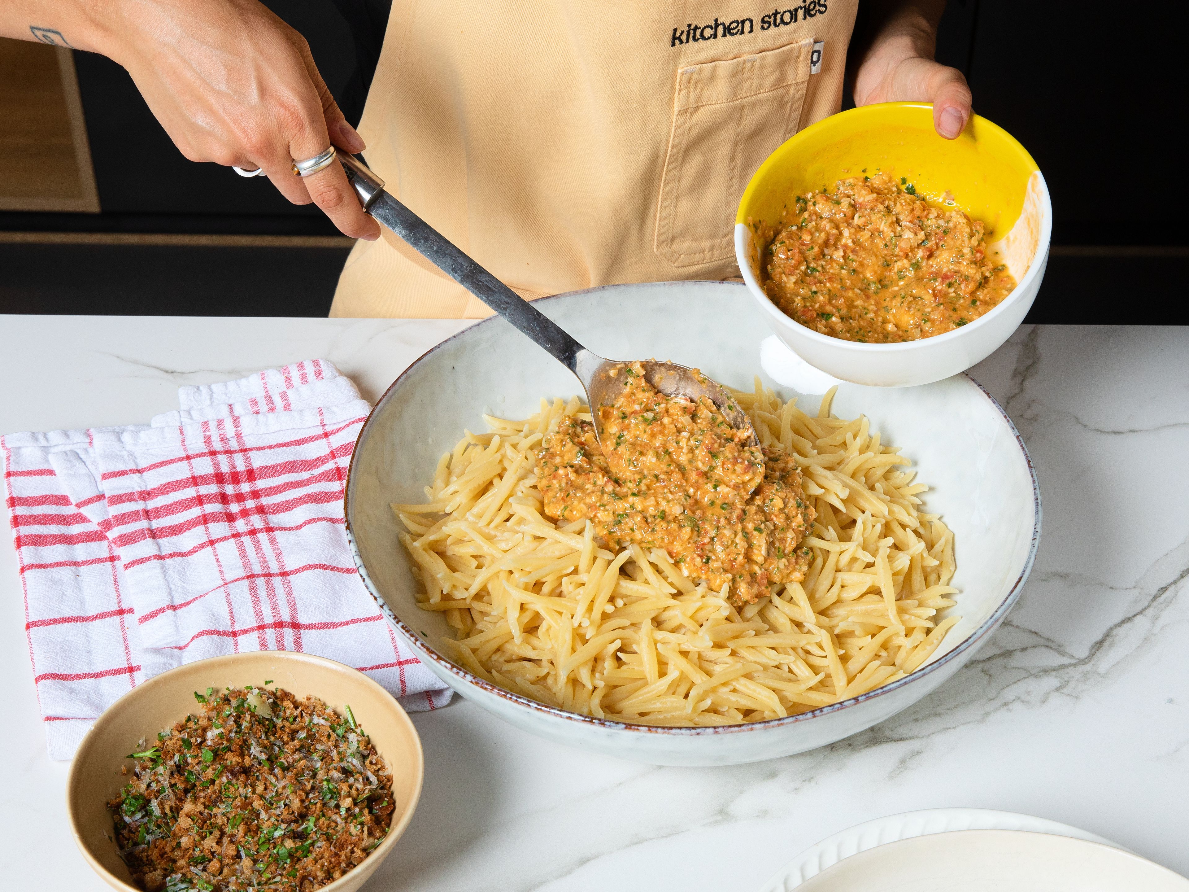 Before draining, reserve some pasta cooking water. Transfer the drained pasta to a large bowl. Add the pesto and a splash of pasta water and toss for approx. 2–3 min., until evenly coated. Divide between plates and top with pangrattato and some lemon zest, if desired.