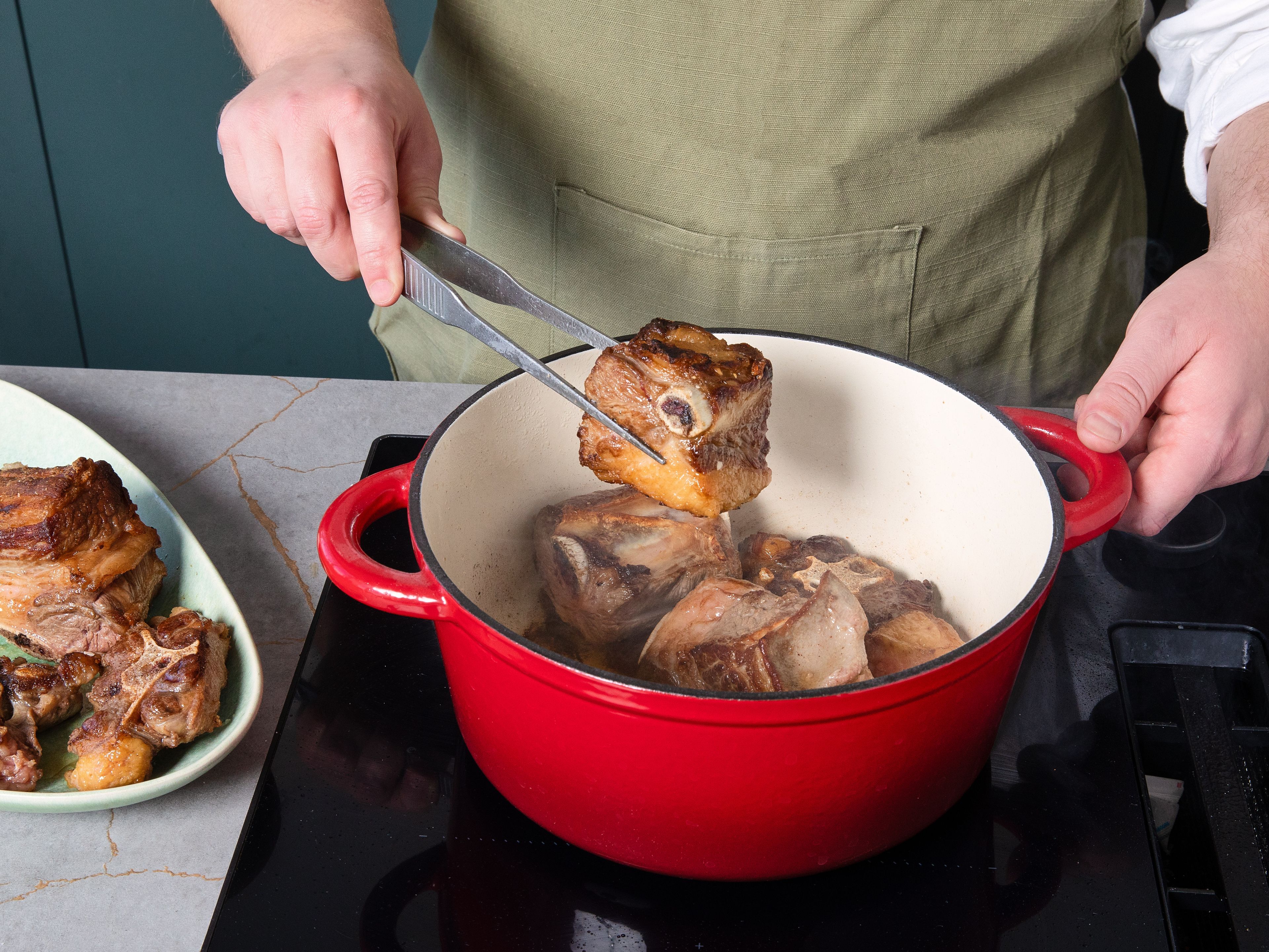 Die Zwiebeln halbieren und schälen. Den Knoblauch schälen. Die Chilischoten entstielen und, je nach gewünschtem Schärfegrad, entkernen. Das Fleisch in einem ofenfesten Topf mit etwas Öl rundherum goldbraun anbraten. Das Fleisch aus dem Topf nehmen. Anschließend die Chilischoten, Zwiebeln, Knoblauch und Tomaten im gleichen Topf kurz anrösten. Mit Brühe ablöschen und zugedeckt ca. 20 Min. köcheln lassen.