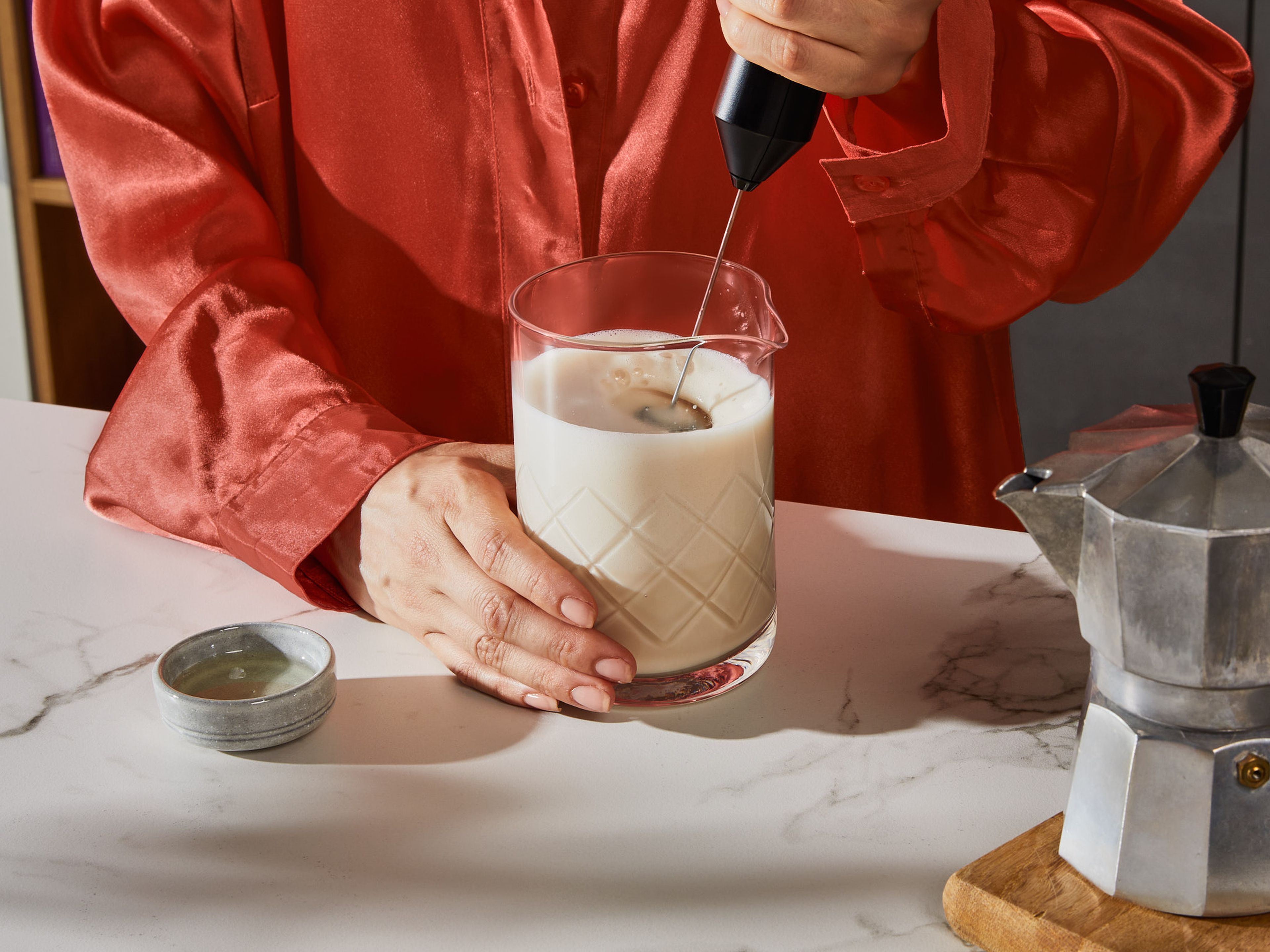 Die Kardamomkapseln aus der Alpro Barista Hafer nehmen. Dann wie gewohnt aufschäumen. Einen starken Espresso aufbrühen und in ein Glas gießen. Agavensirup hinzufügen und umrühren.