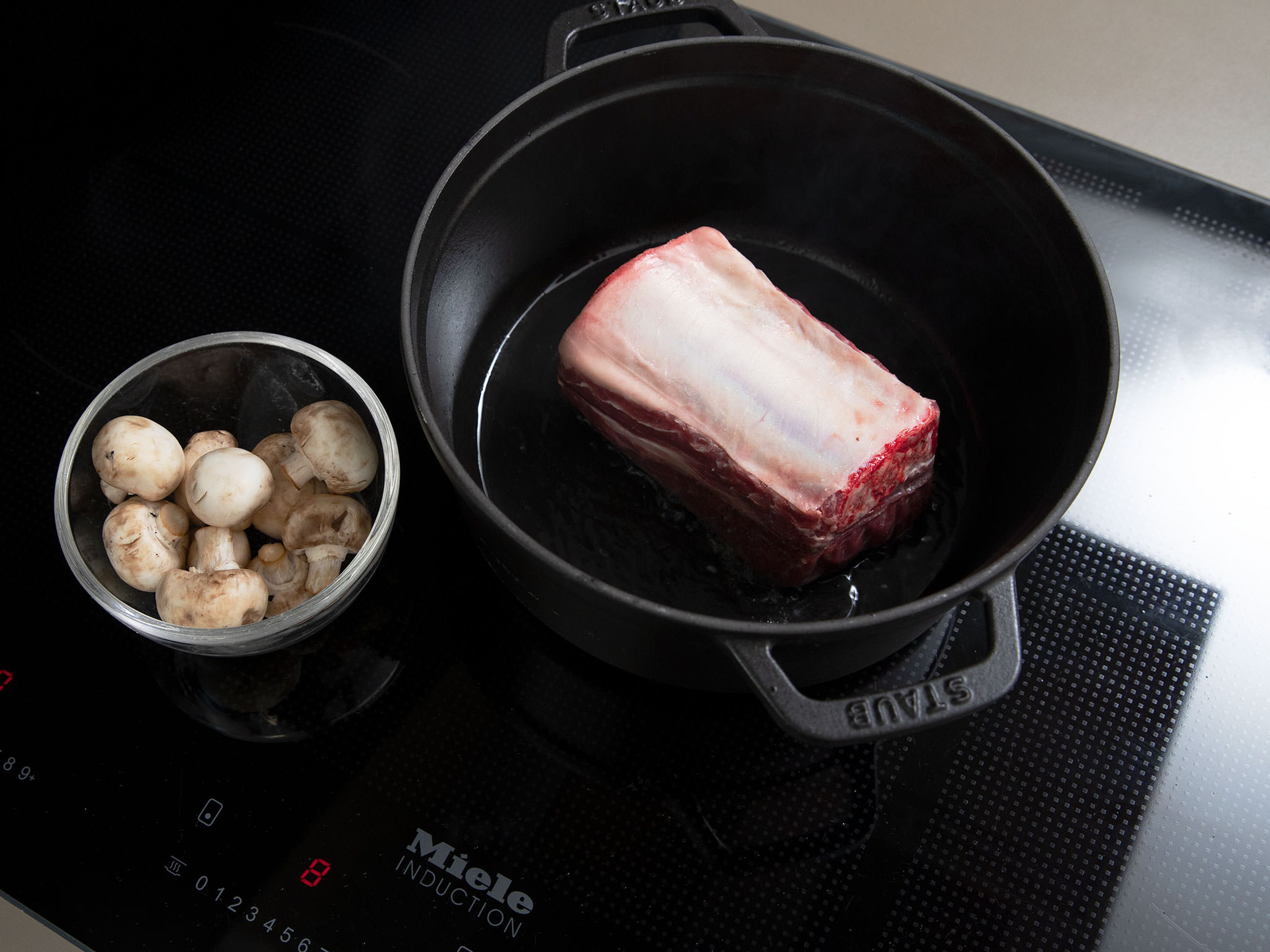 Peel and thinly slice garlic. Season short ribs with salt and pepper. Heat oil in a pot over medium-high heat and sear meat on both sides, then add garlic.