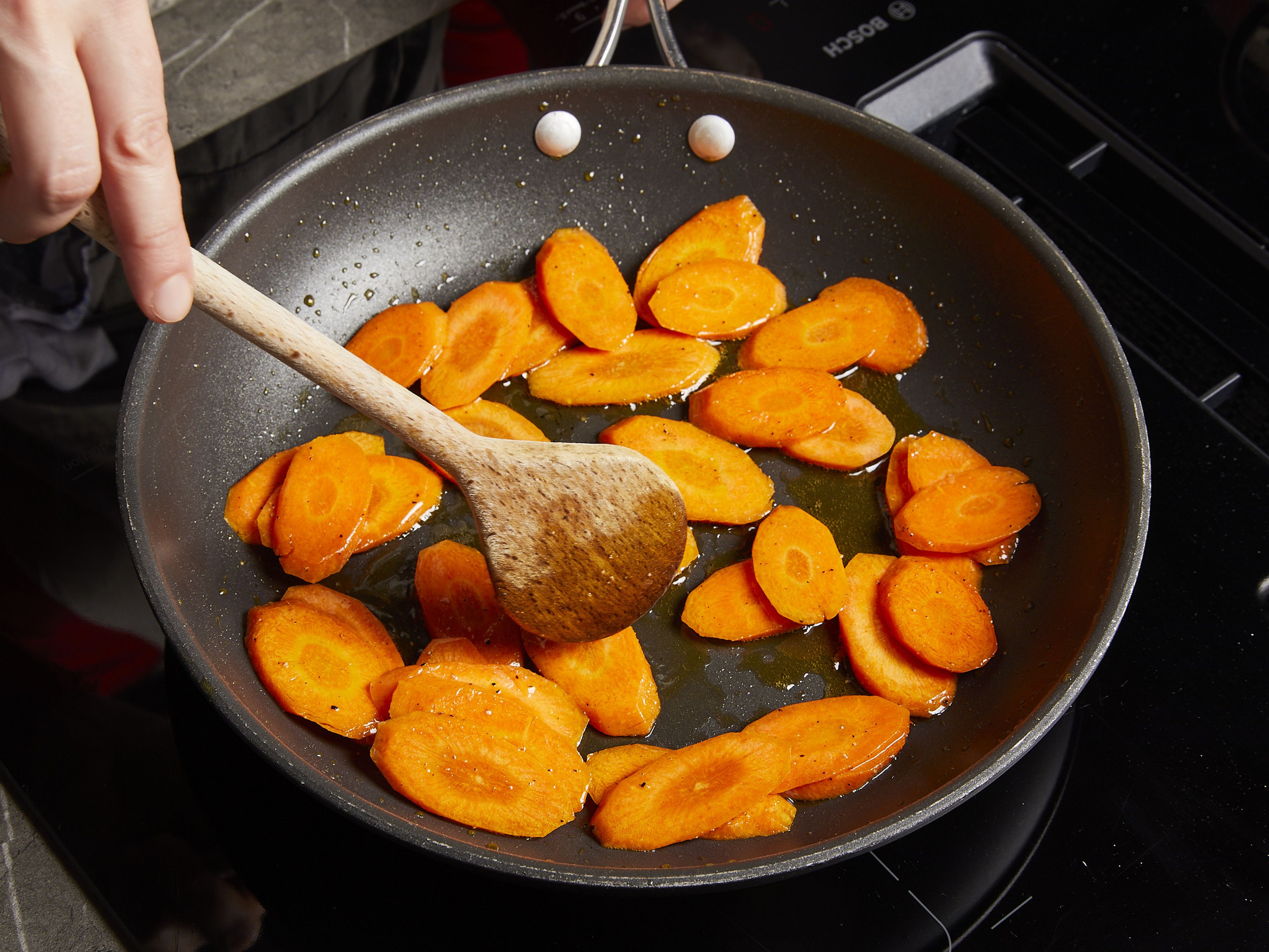 In der Zwischenzeit das restliche Öl in einer Pfanne erhitzen und die Karottenscheiben darin bei mittlerer Hitze ca. 3–5 Min. braten, dann mit Salz würzen. Das Pesto mit der Sahne in einer kleinen Schüssel verrühren. Parmesan reiben und etwas zum Garnieren beiseitestellen.