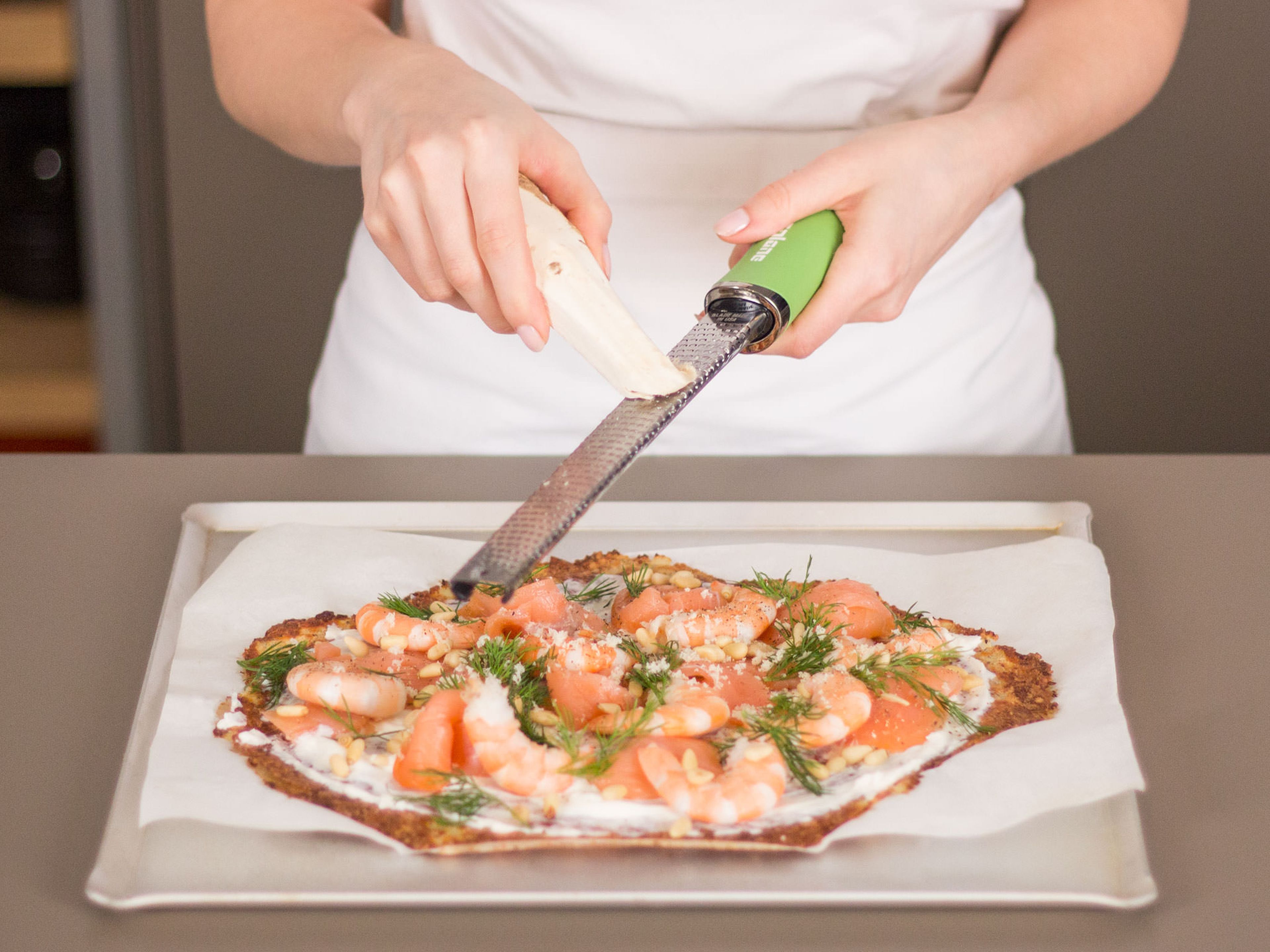 Spread ricotta evenly over crust. Then, top pizza off with salmon, shrimp, pine nuts, and freshly grated horseradish. Garnish with fresh dill.