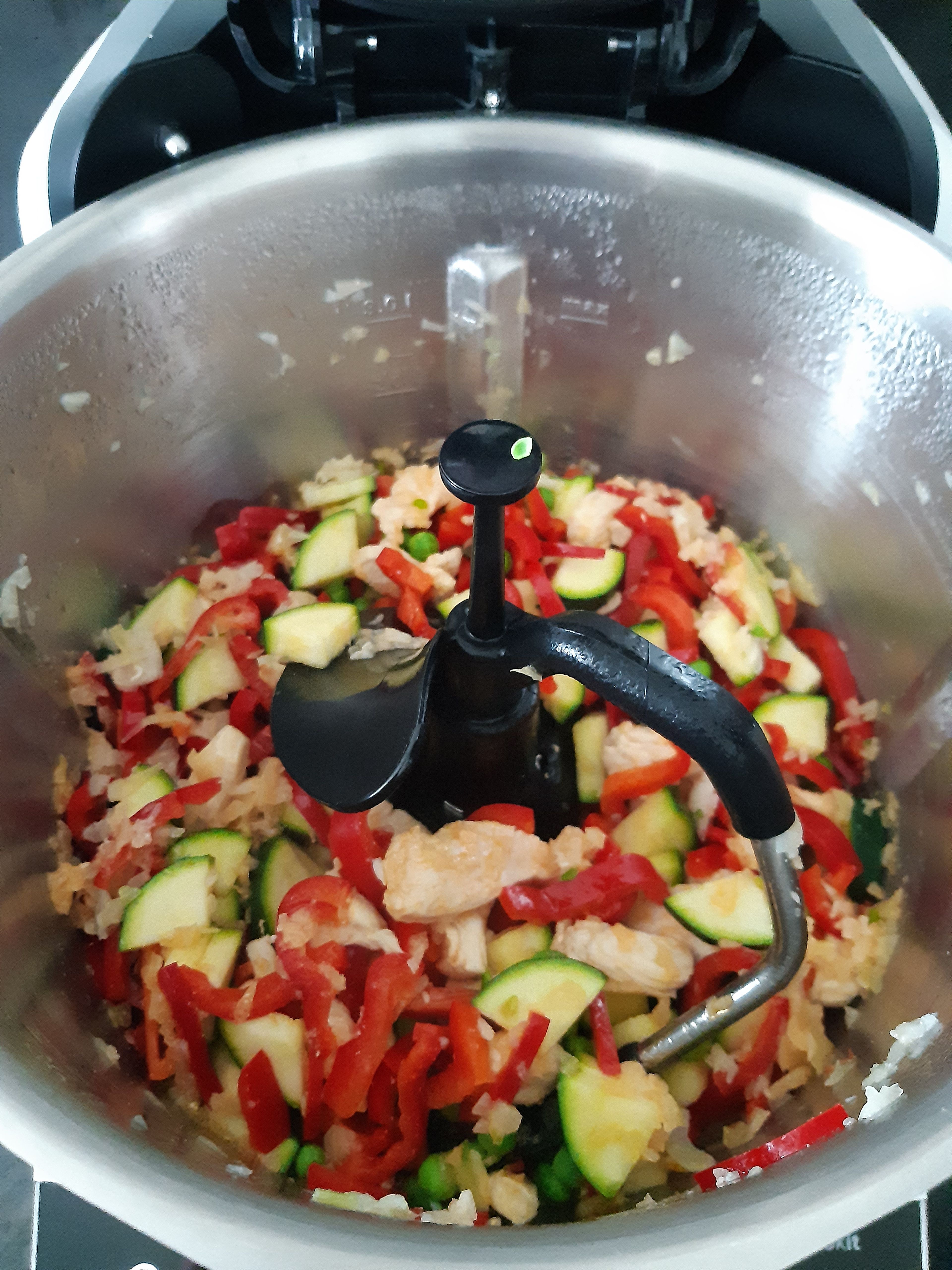 Die gewürfelte Paprika, Zucchini und die Erbsen in den Topf geben und weiter bei geschlossenem Deckel, ohne Messbecher, anbraten (3D-Rührer | Stufe 4 | 100°C | 3 Minuten).
