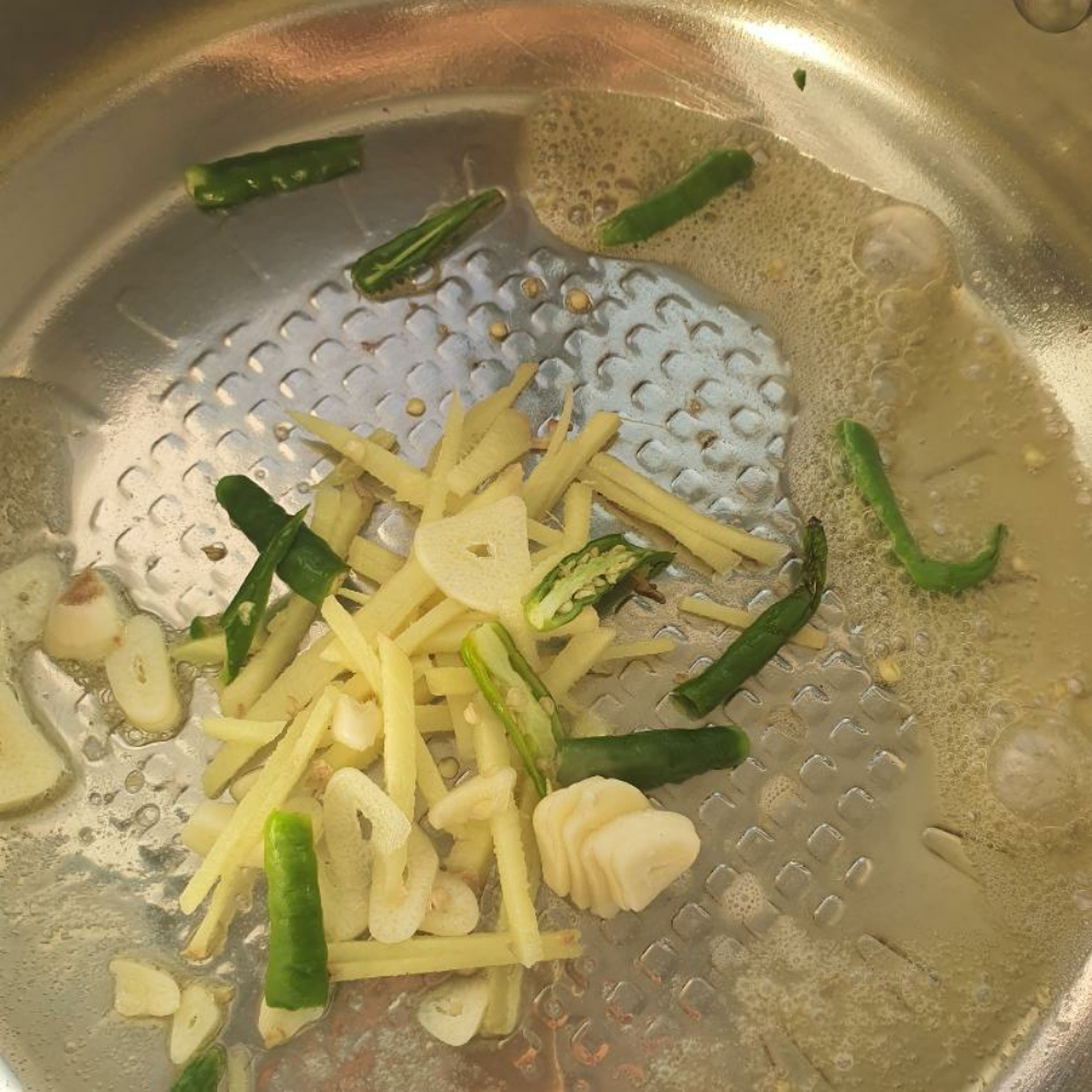 To a pan add butter, sliced ginger, garlic and green chillies and saute till they turn golden.
