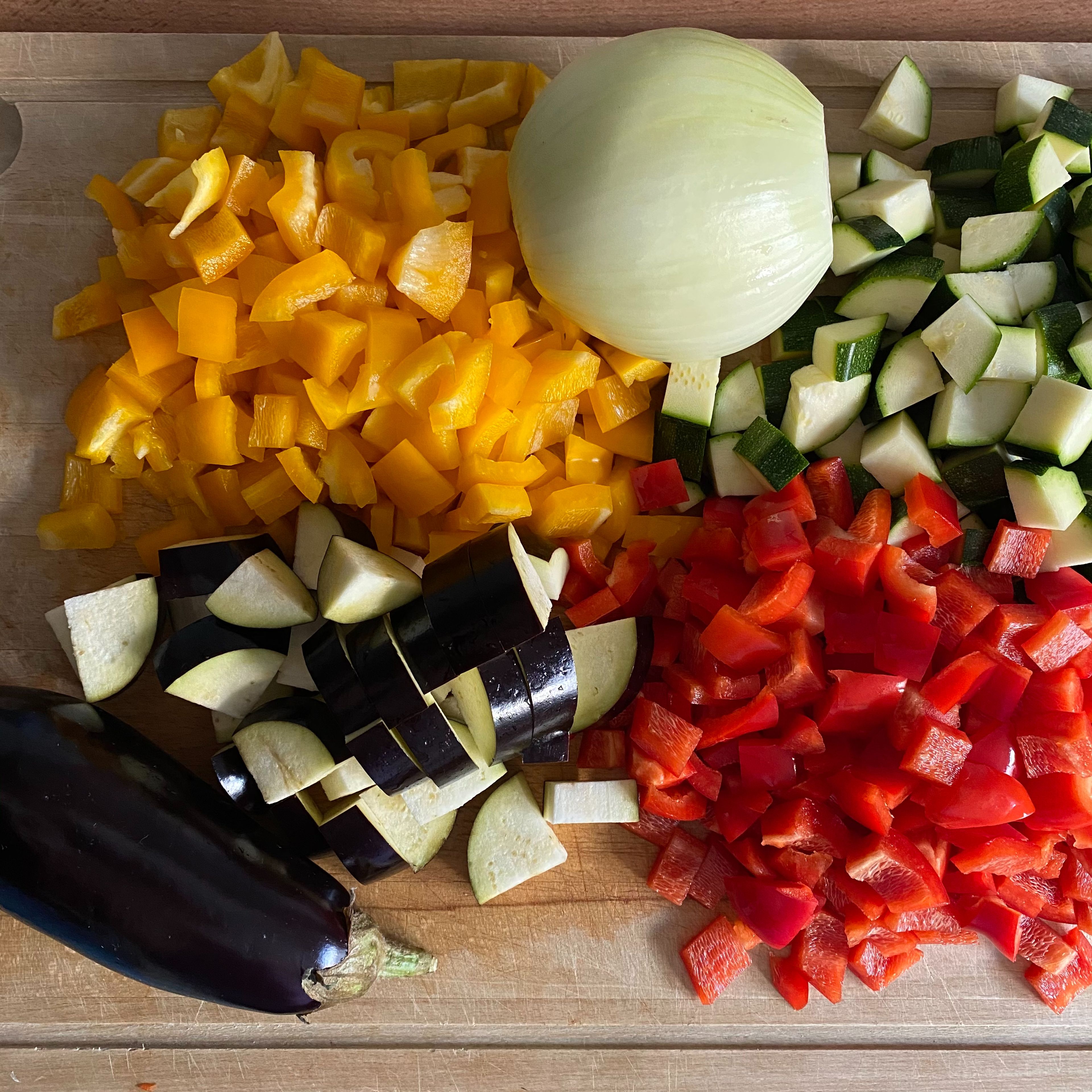Zucchinis und Auberginen längs vierteln und in 1cm dicke Stücke schneiden. Die Paprikas und die Gemüsezwiebel in 1cm große Würfel schneiden.